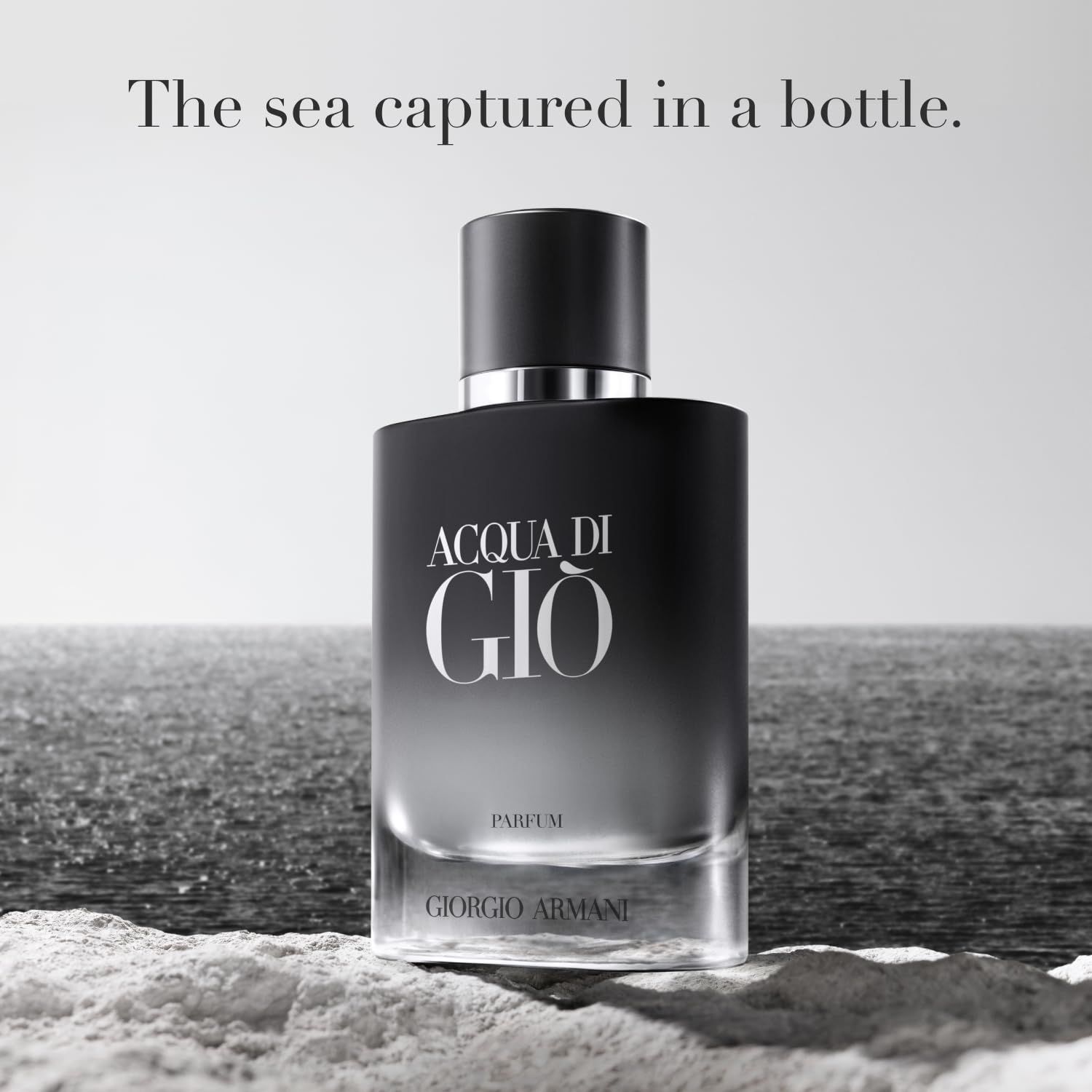 Flacone Acqua di Giò Parfum davanti a sfondo marino. Flacone nero con logo bianco.