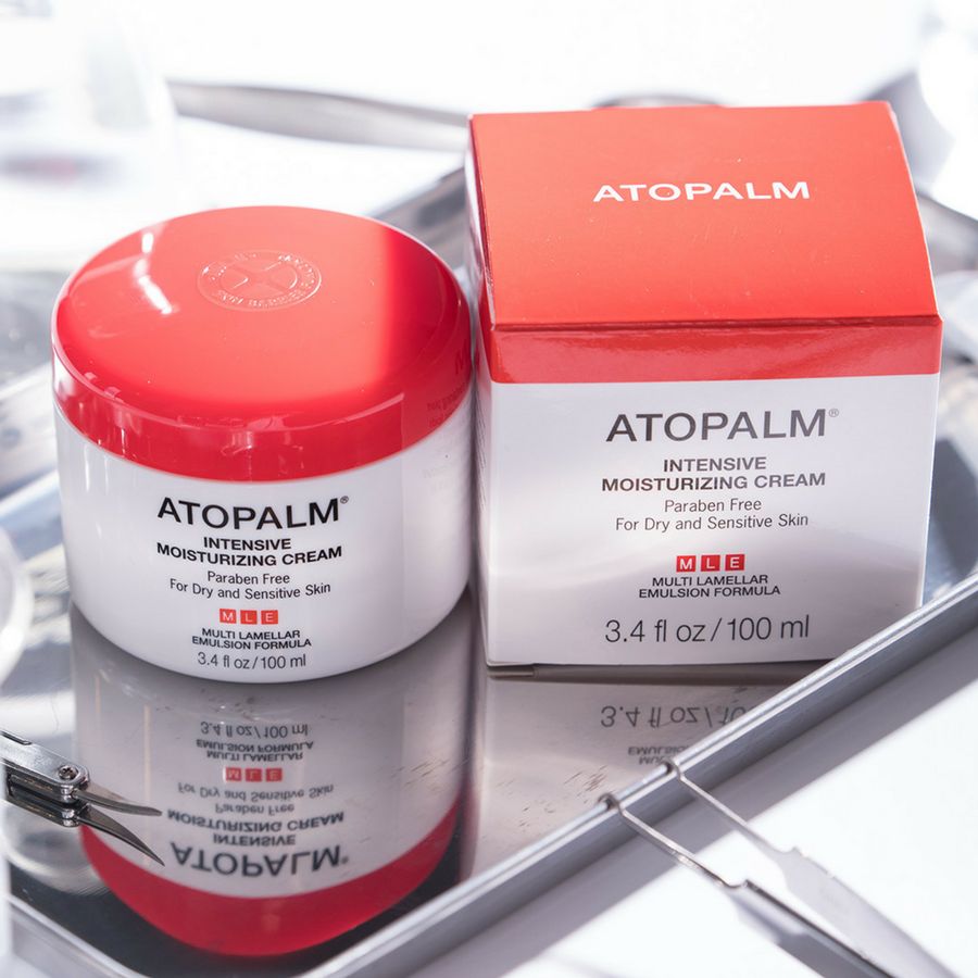 Confezione del prodotto con vasetto e scatola. Scritta: ATOPALM INTENSIVE MOISTURIZING CREAM. Su superficie argentata.