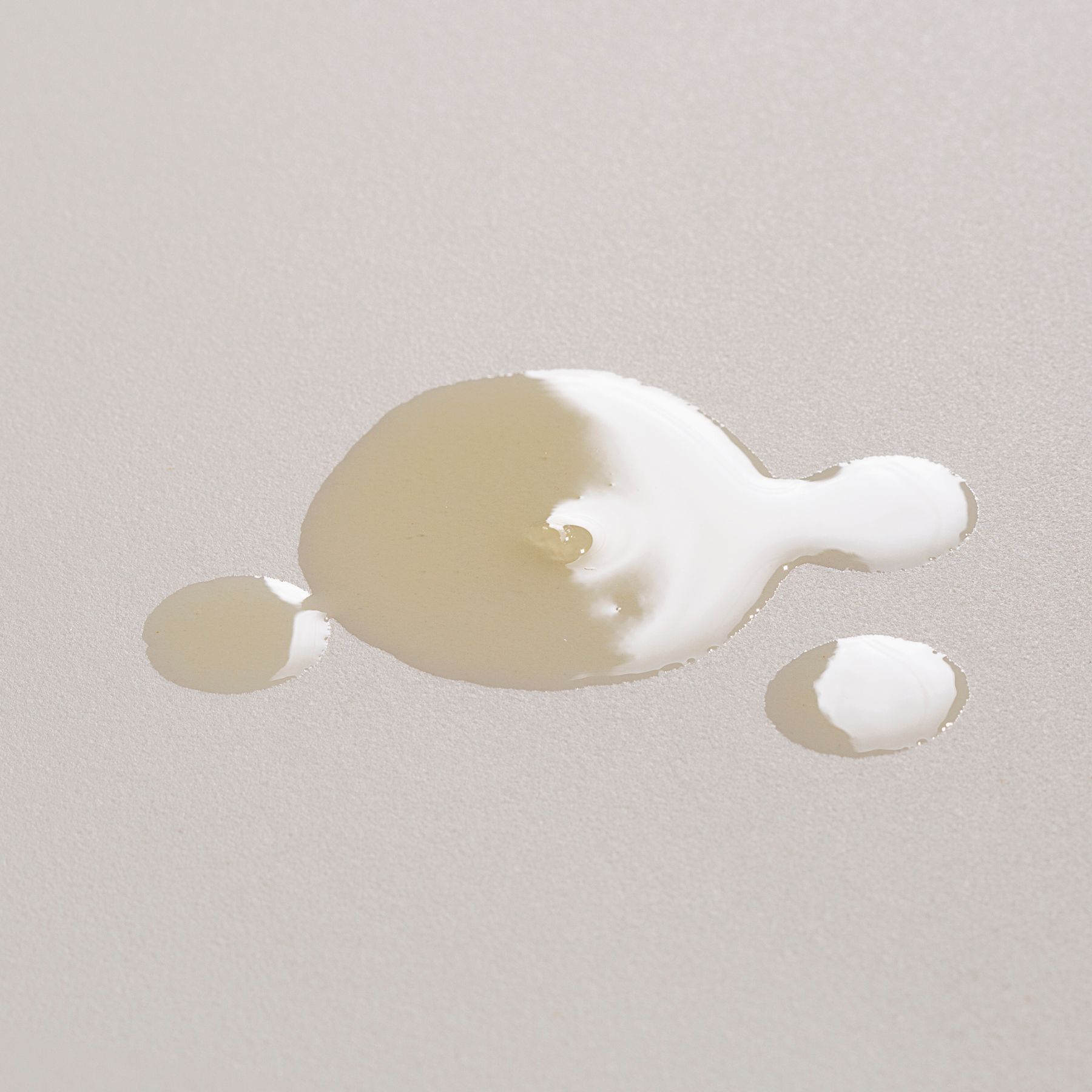 Una macchia di olio dorato su sfondo chiaro.