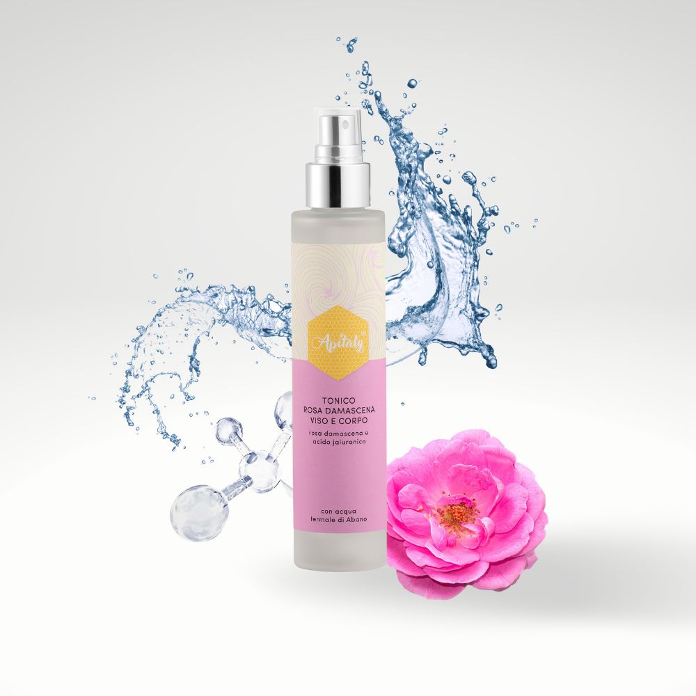 Flacone cilindrico con vaporizzatore. Etichetta rosa con nome prodotto e logo. Spruzzi d'acqua e rosa.