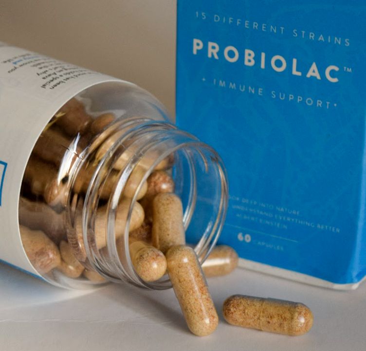 Flacone di capsule probiotiche Aavalabs rovesciato, capsule sparse.