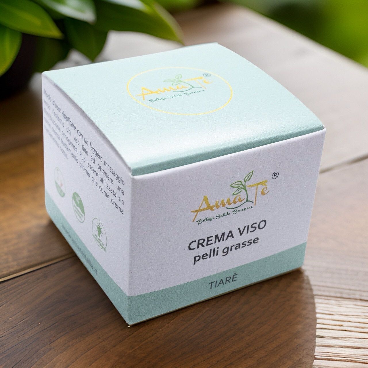 Confezione di Amatè Crema Viso pelli grasse Tiarè su superficie in legno. Scatola bianca con dettagli verde chiaro. Nome e logo visibili.