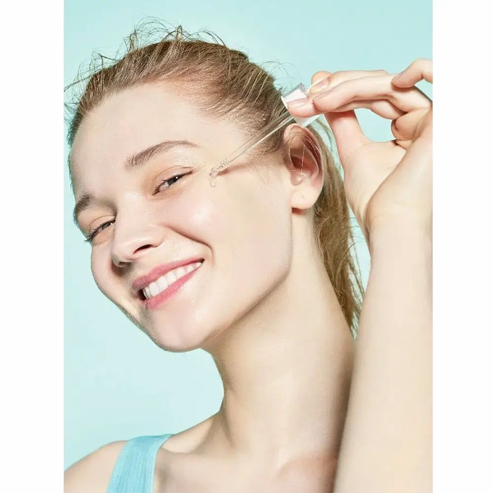 Donna con applicatore di siero. Il siero viene applicato sulla pelle. Sfondo blu.