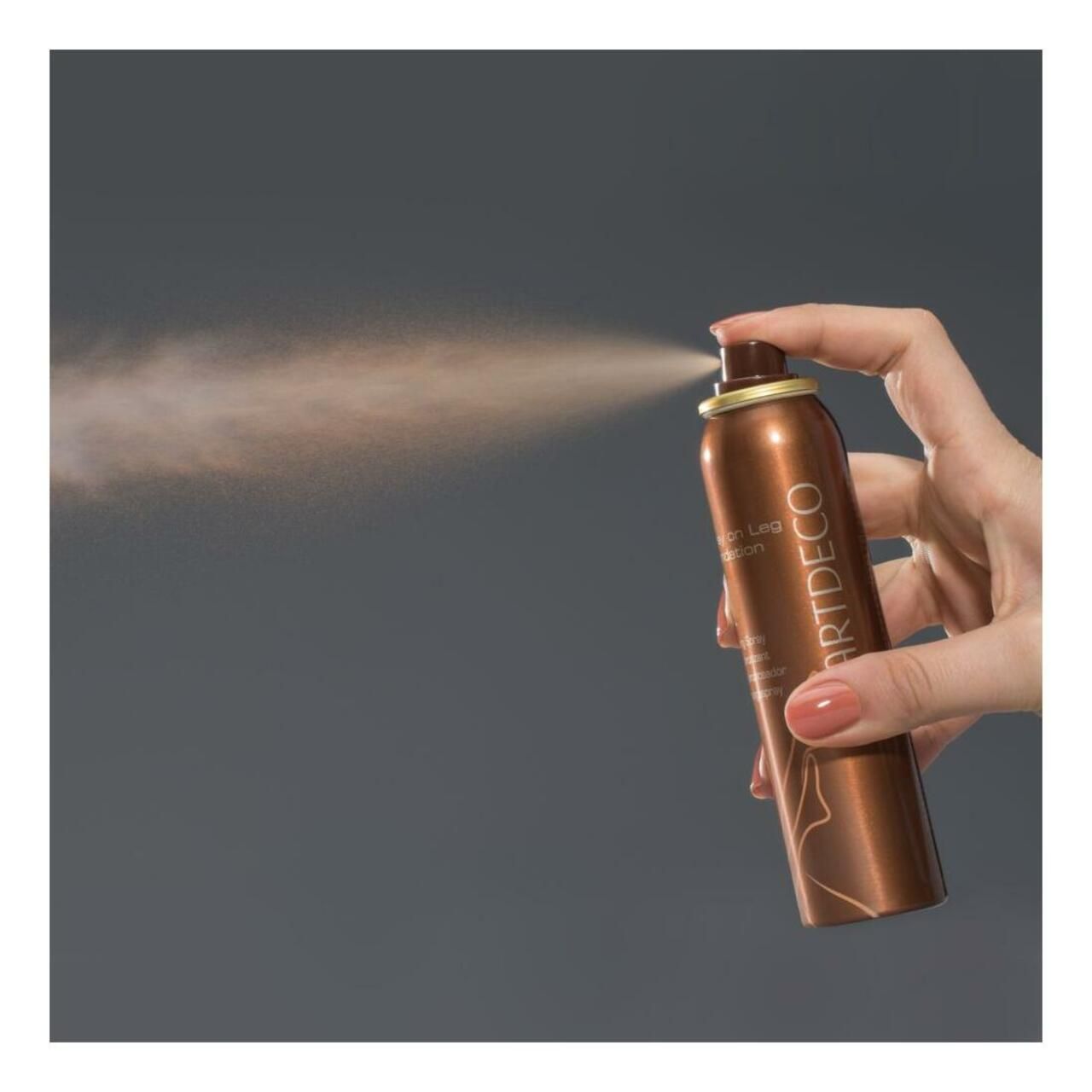 Bomboletta spray Artdeco Spray on Leg Foundation. Nebulizzazione visibile. Tenuta in mano.