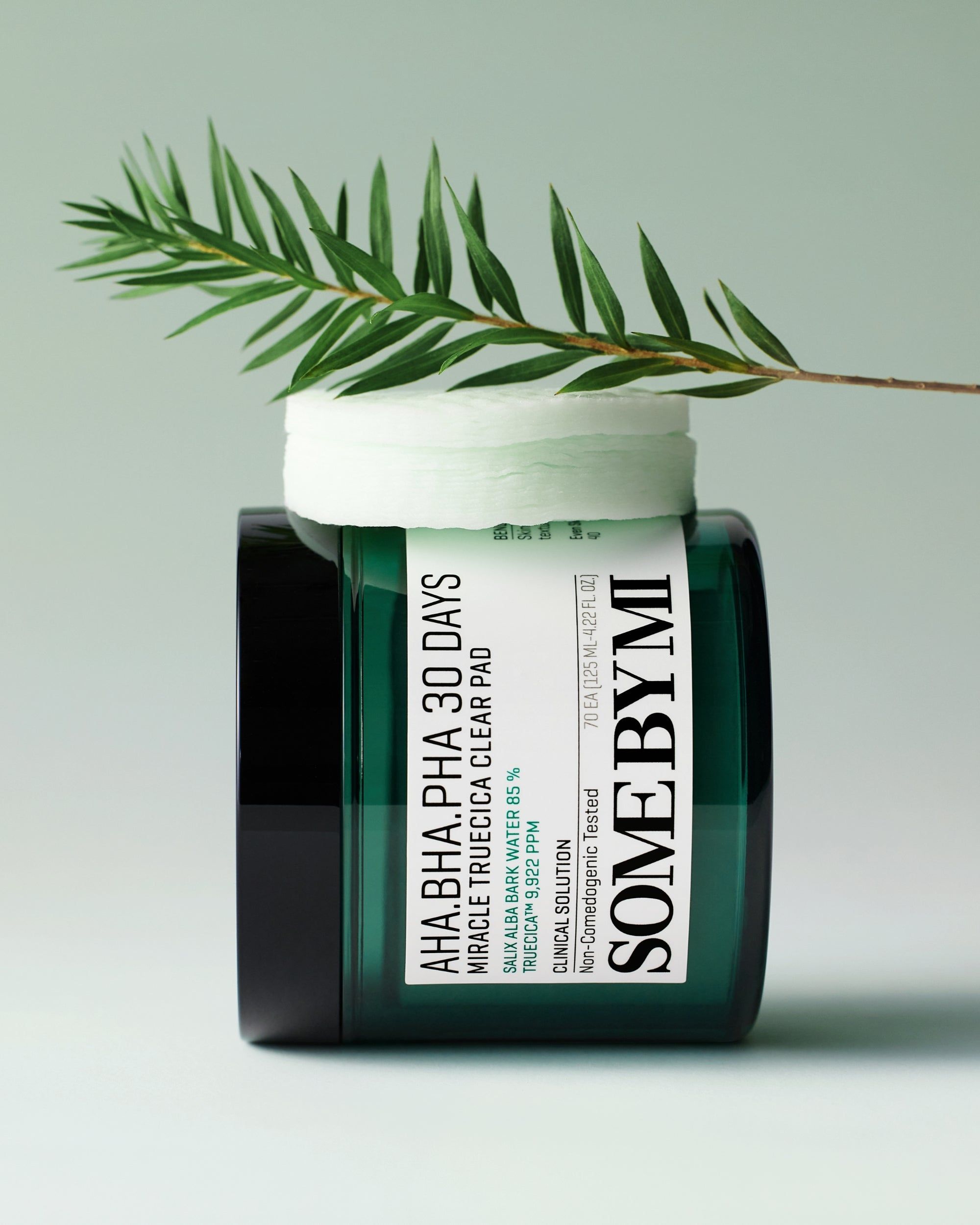 SOMEBYMI AHA-BHA-PHA Clear Pad in barattolo di vetro verde con coperchio e decorazione fogliare.