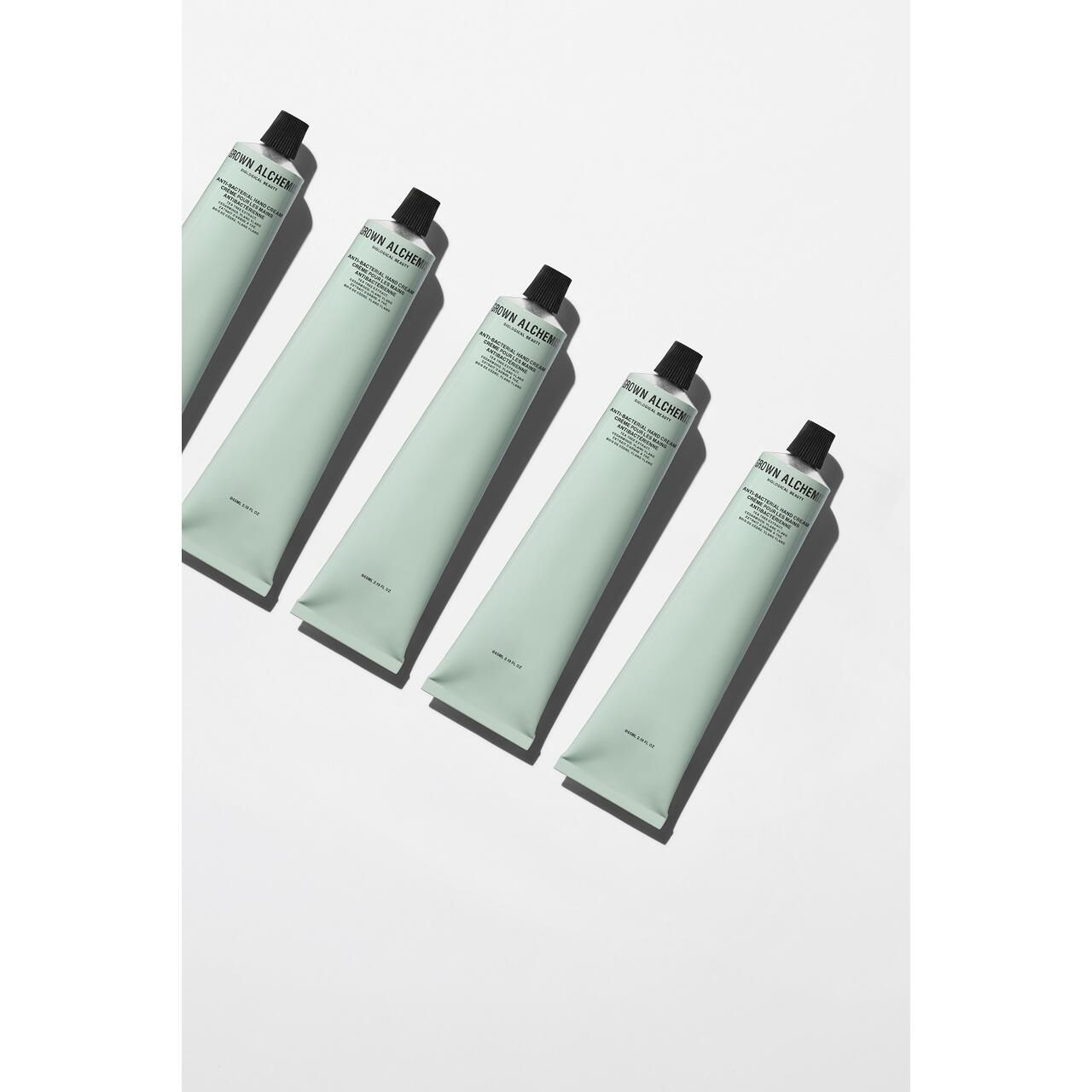 Cinque tubi verde chiaro con tappo nero. Scritta: Grown Alchemist, Anti-Bacterial Hand Cream. Su sfondo bianco.