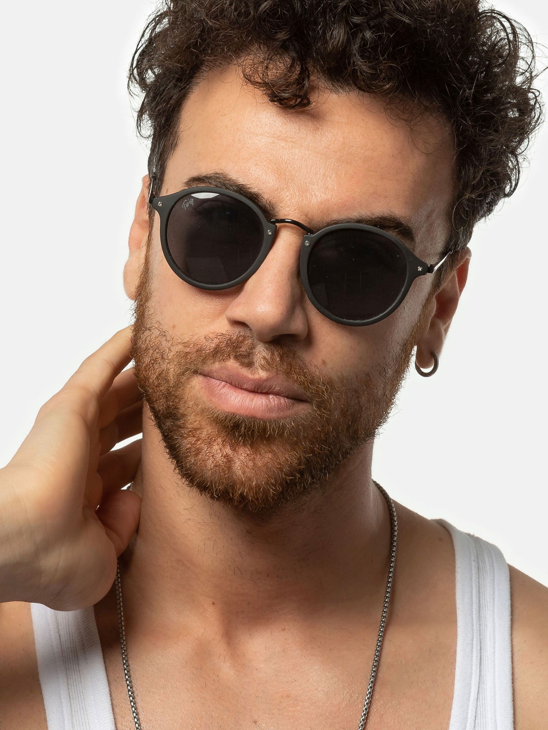 Uomo con occhiali da sole. Lenti rotonde nere, montatura nera. Indossa una canotta.