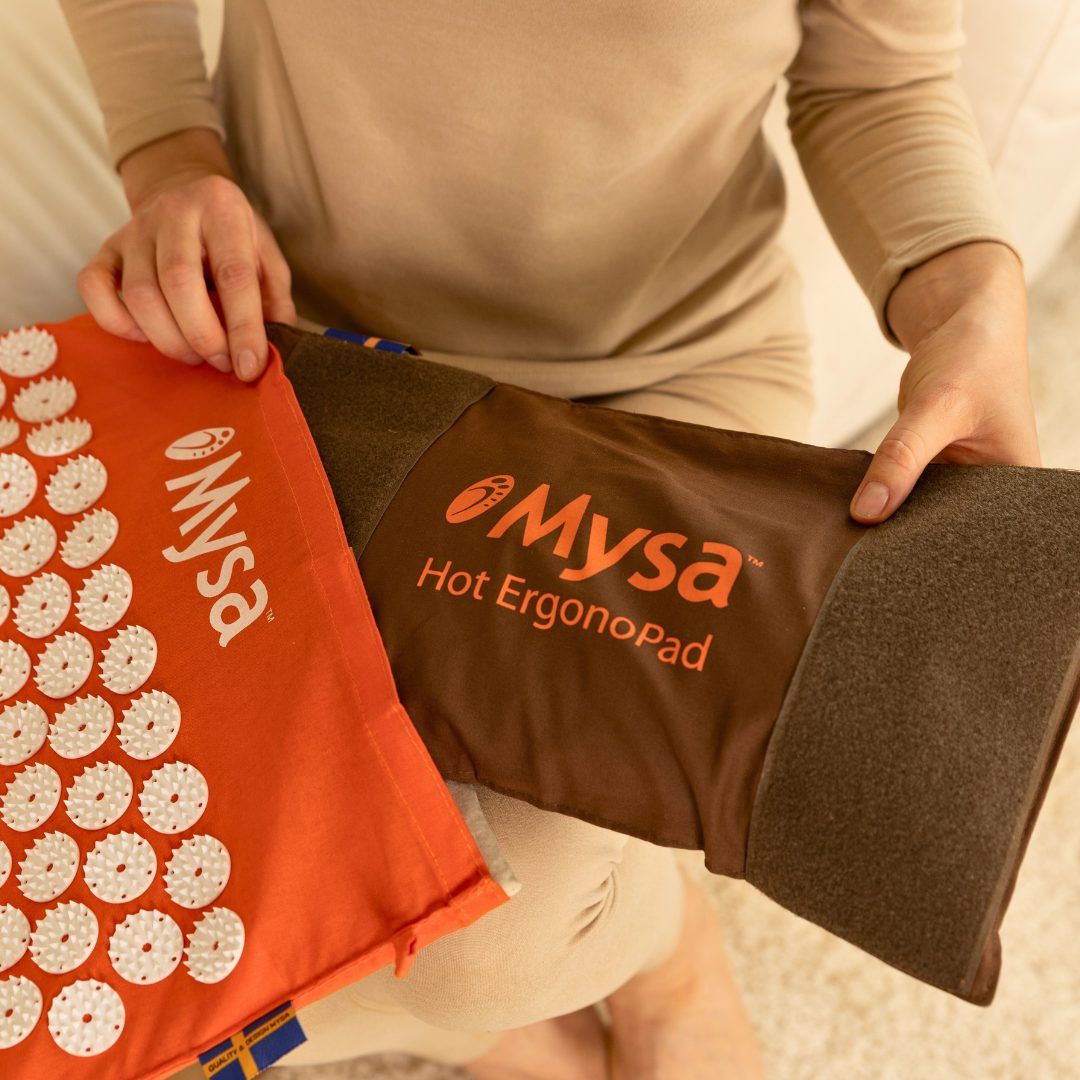 Mani che tengono un cuscino arancione con punte bianche e un cuscino marrone. Entrambi hanno il logo Mysa.