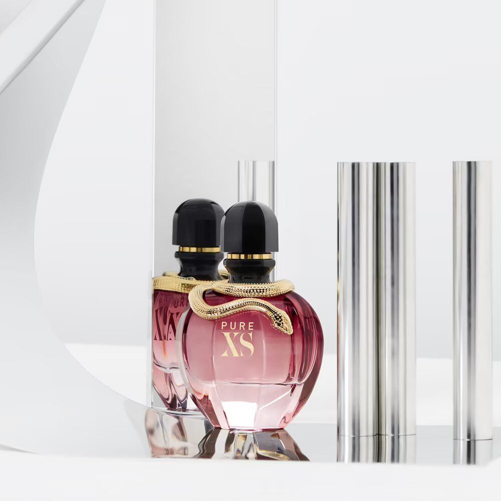 Due flaconi di profumo. Flaconi rotondi, rosa trasparente, serpenti dorati. Sfondo con colonne e arco argentati.