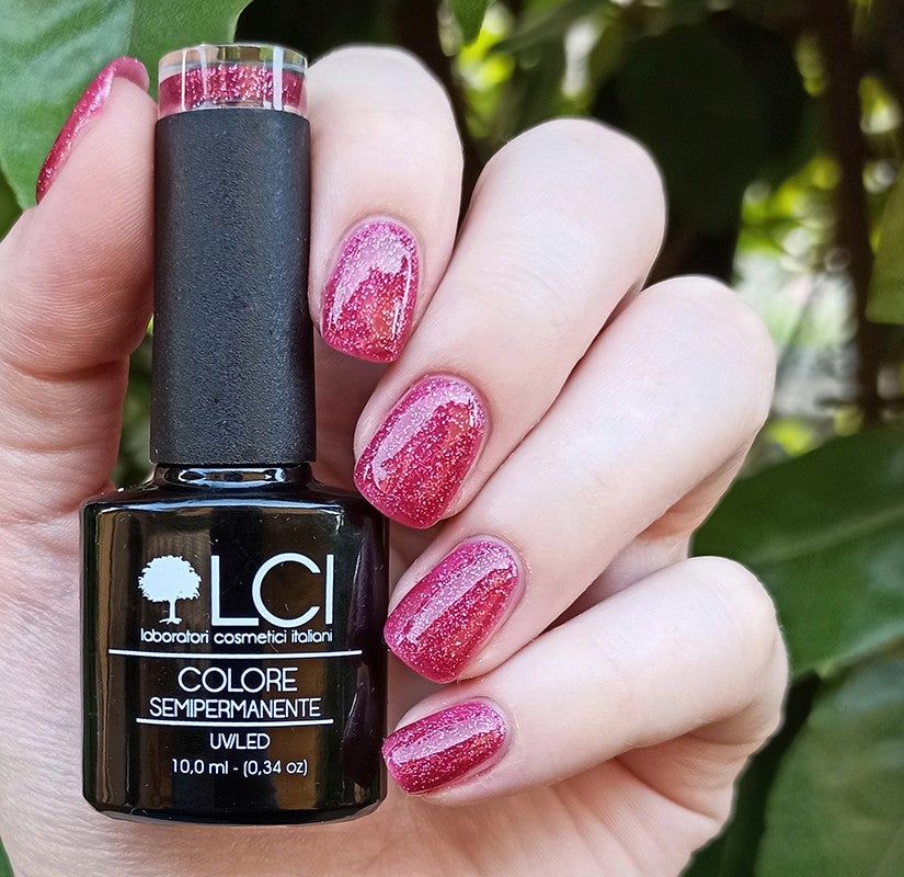 Flacone smalto fucsia in mano. Unghie smaltate. Scritta: LCI, Colore Semipermanente, UVLED.