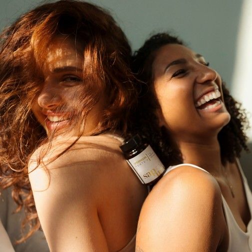 Due donne sorridenti. Una tiene in mano un flacone marrone di capsule di spermidina. Scritta: Spermidina Forte +, 100% vegano. Logo SAPURA.