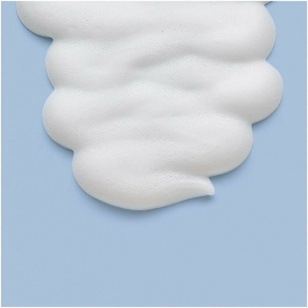 Primo piano di mousse bianca su sfondo azzurro. Struttura della schiuma con contorni ondulati.