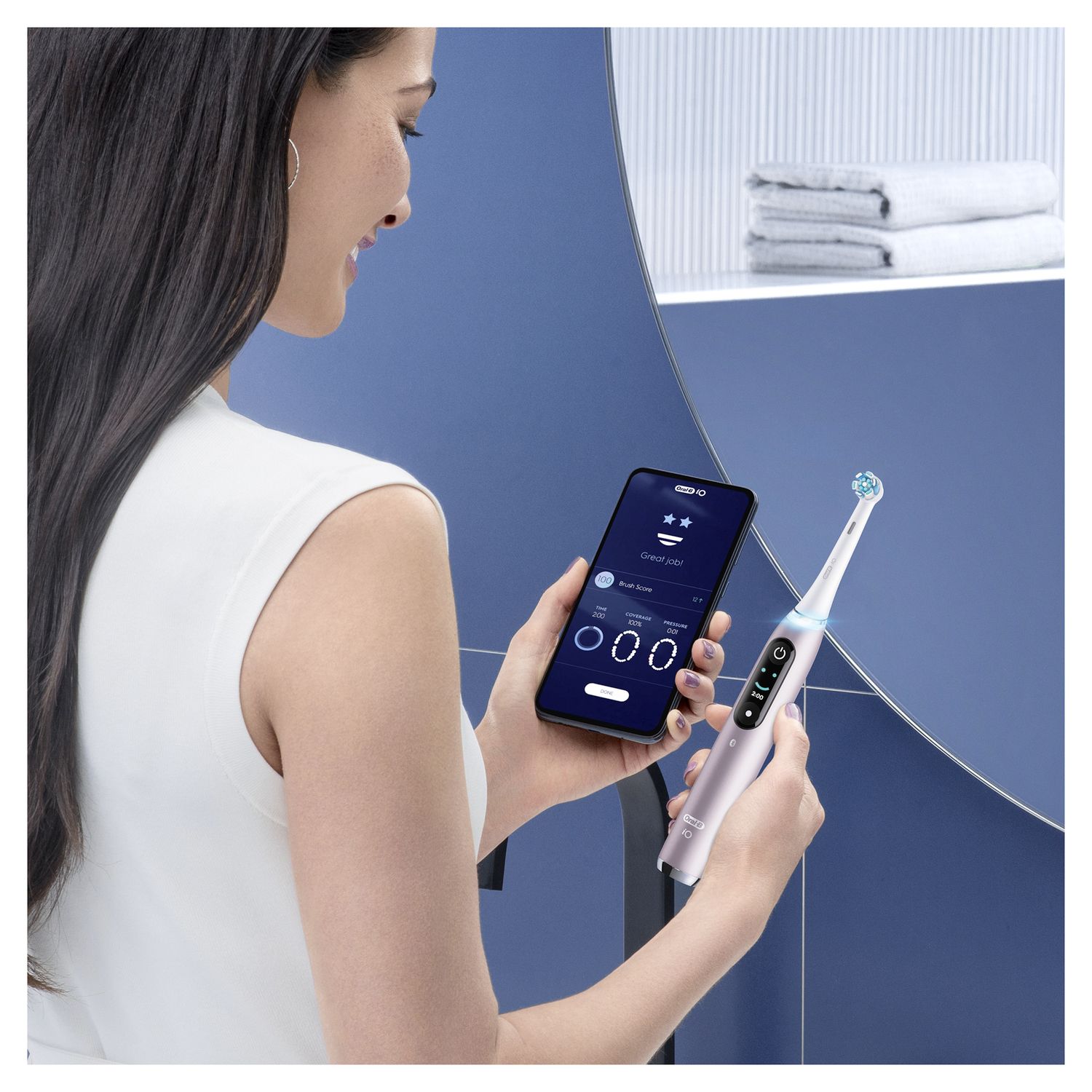Donna che tiene in mano uno smartphone e uno spazzolino elettrico. L'app dello spazzolino è visibile sullo smartphone.