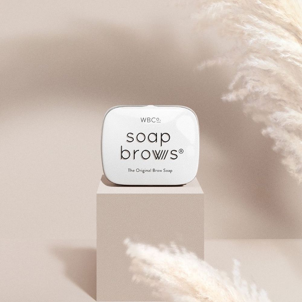 Scatola bianca con scritta su un piedistallo. Sfondo con erba della pampa.