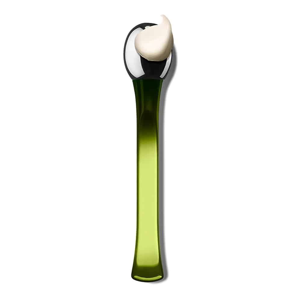 Applicatore verde con testa metallica, su cui è presente una sostanza color crema.