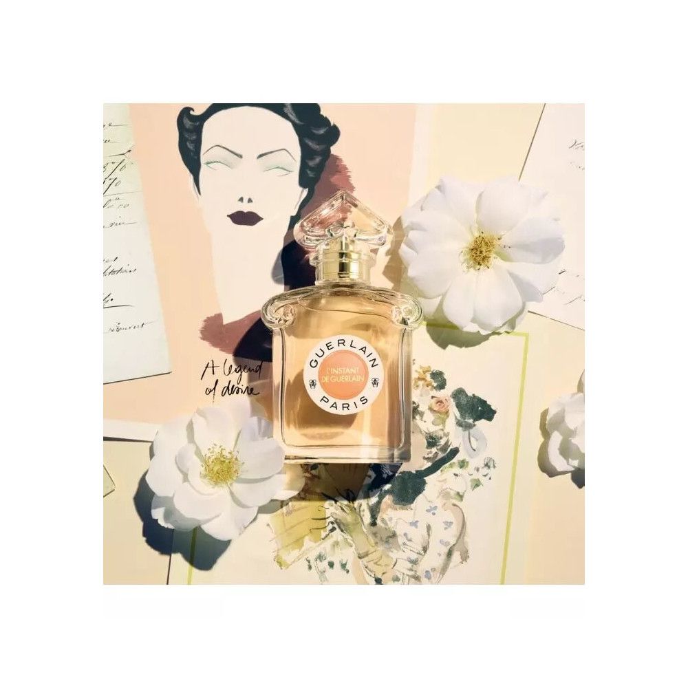 Flacone di profumo con etichetta rotonda e scritta. Su carta con fiori e disegni. Fiori bianchi.