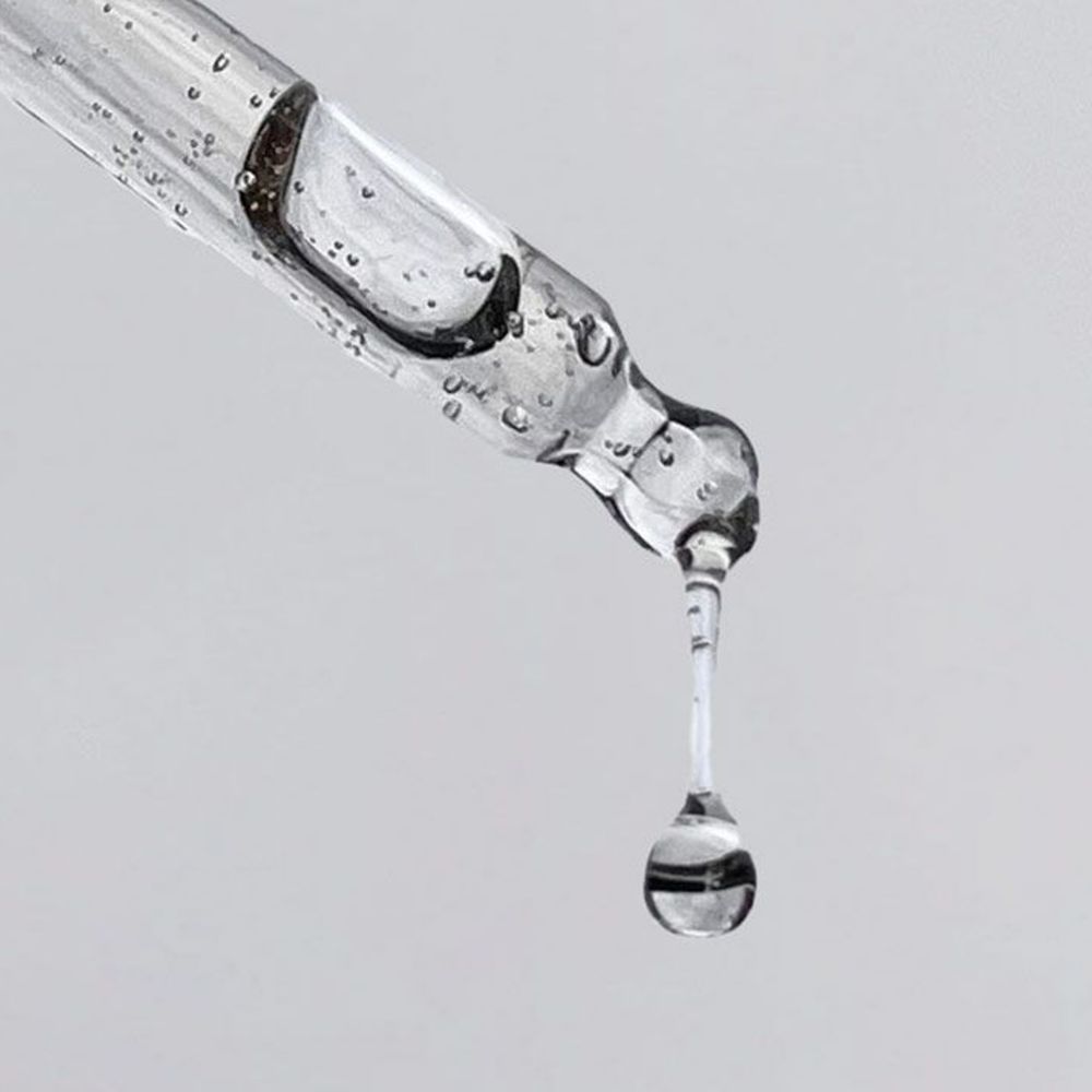 Goccia di liquido limpido cade da un contagocce, primo piano.