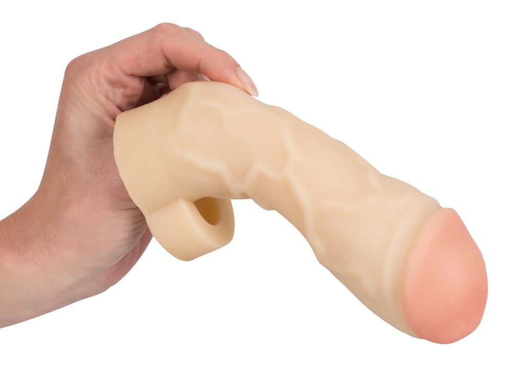Fodera per pene beige tenuta da una mano. Punta rosa. Base con apertura. Superficie dettagliata.