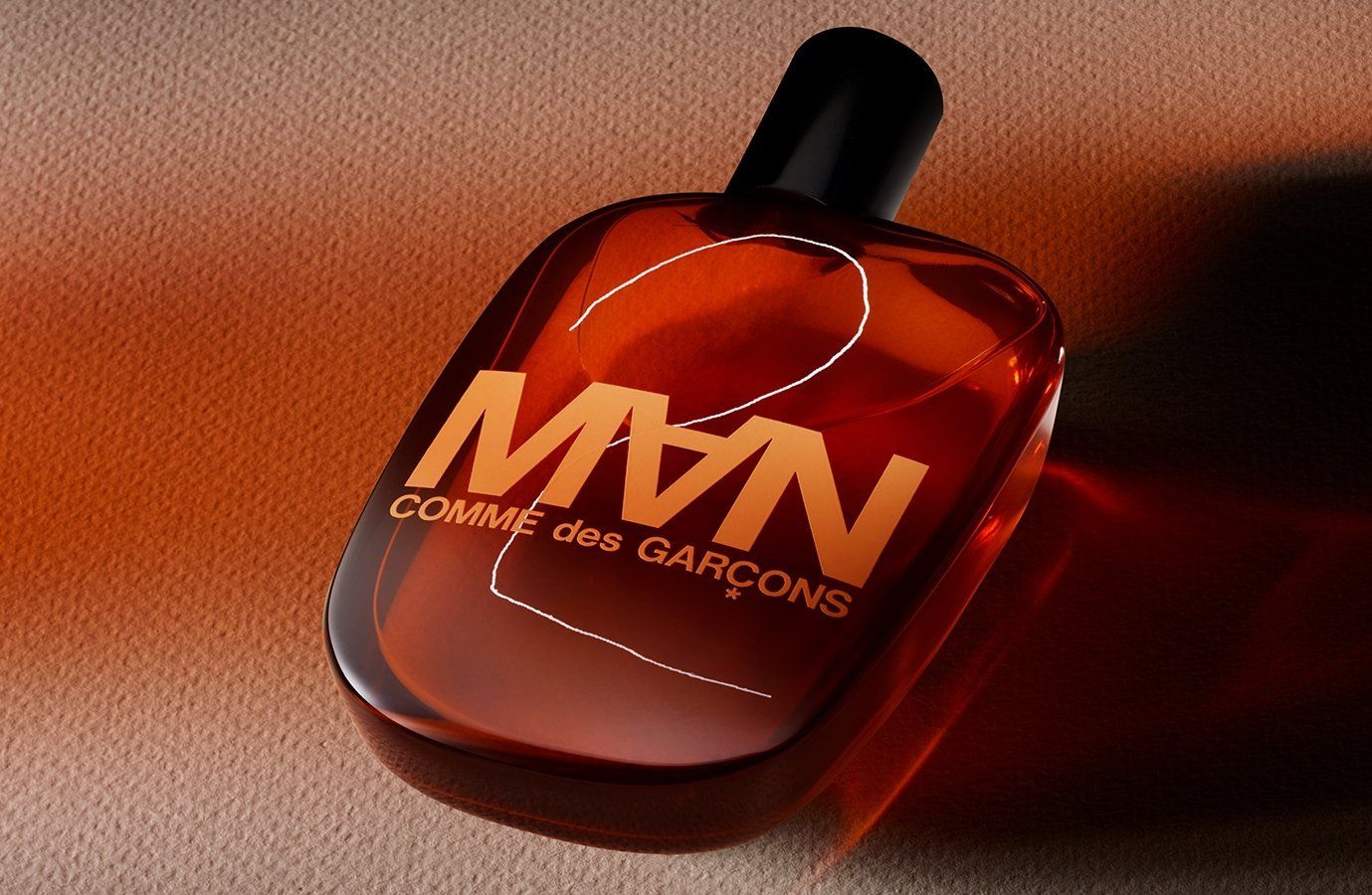 CDG 2 MAN Eau de Toilette Spray. Liquido marrone nel flacone. Tappo nero. Logo e scritta.