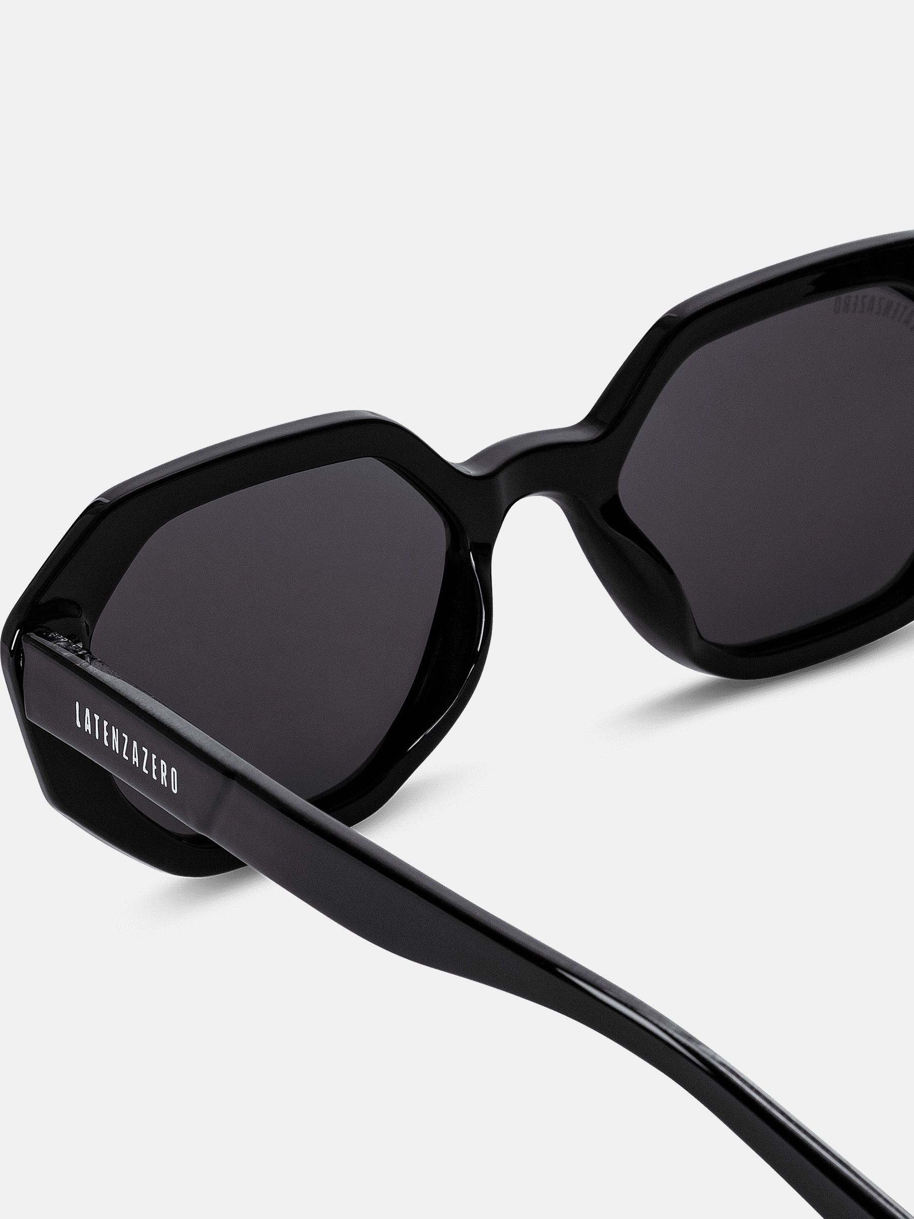 Primo piano di occhiali da sole neri con lenti ottagonali. Il nome del marchio è visibile sull'asta.