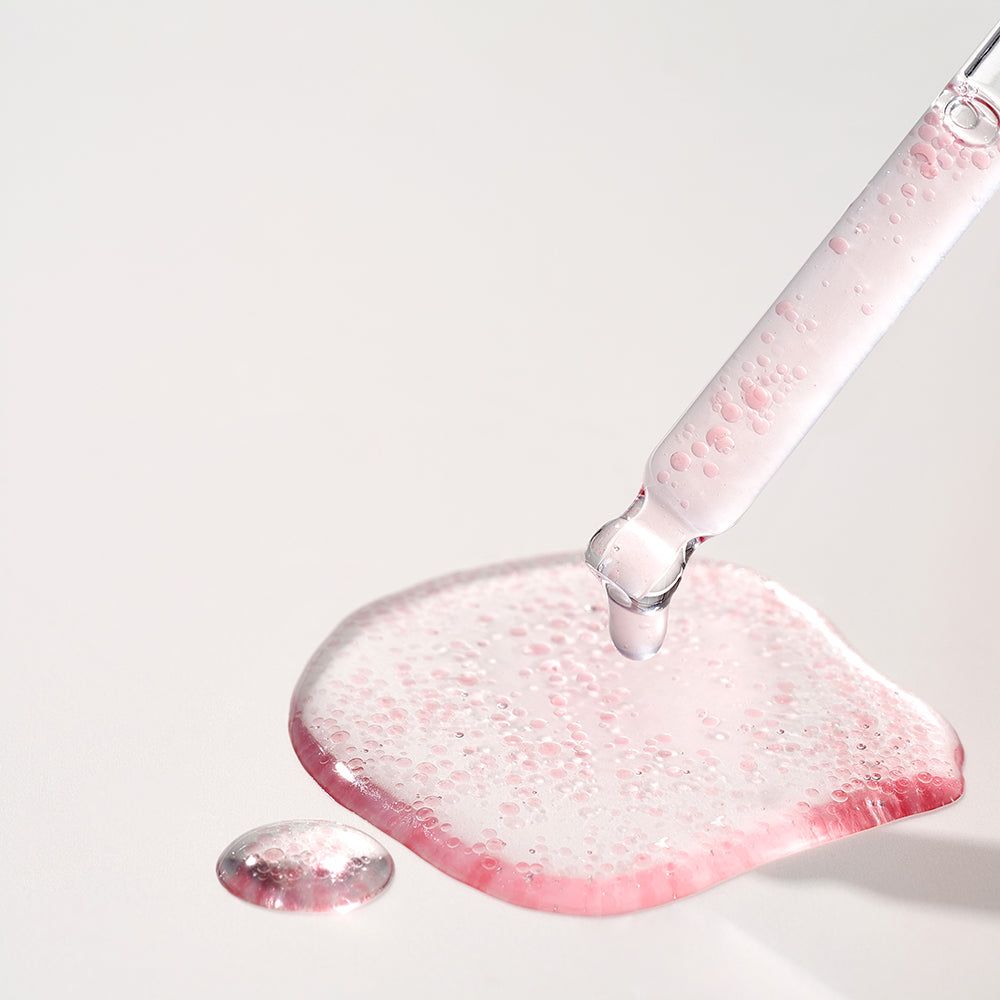 Siero con particelle rosa gocciola da un contagocce su una superficie.