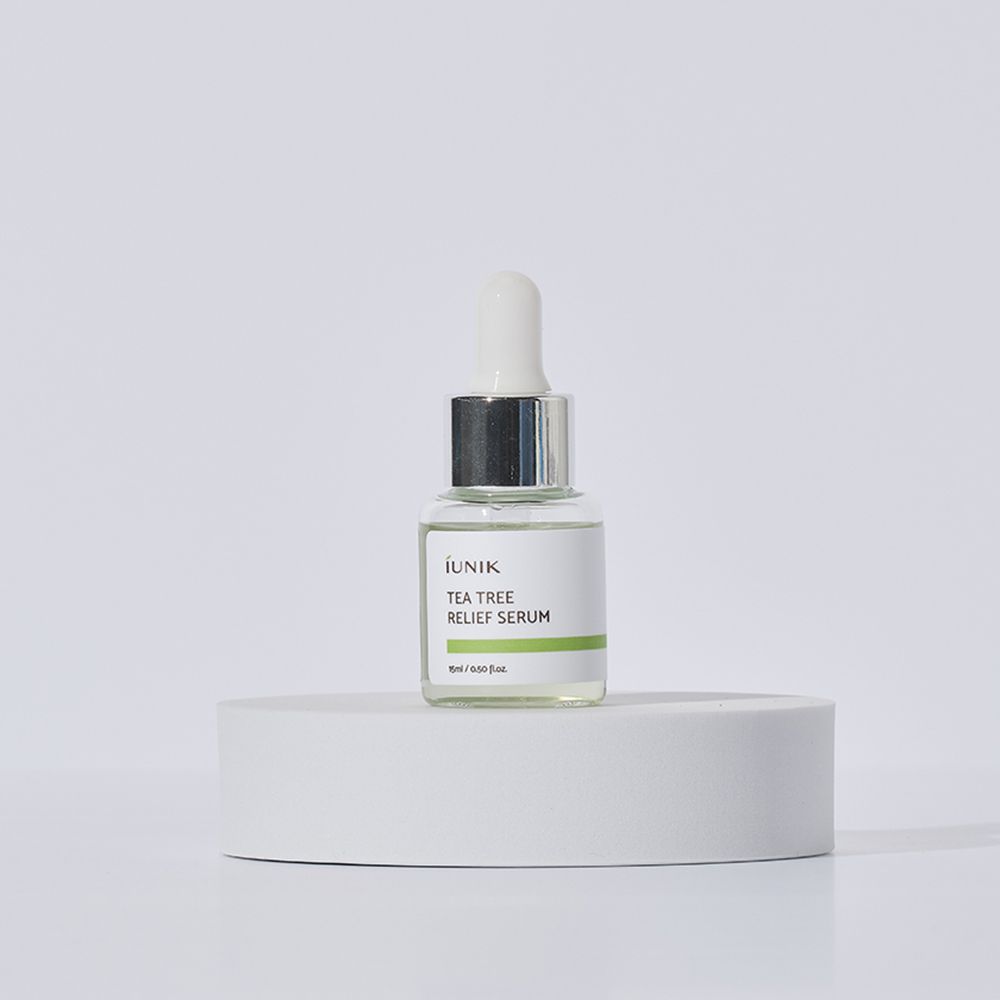 Flacone di siero con contagocce. Scritta: iUNIK Tea Tree Relief Serum. Su piedistallo bianco.