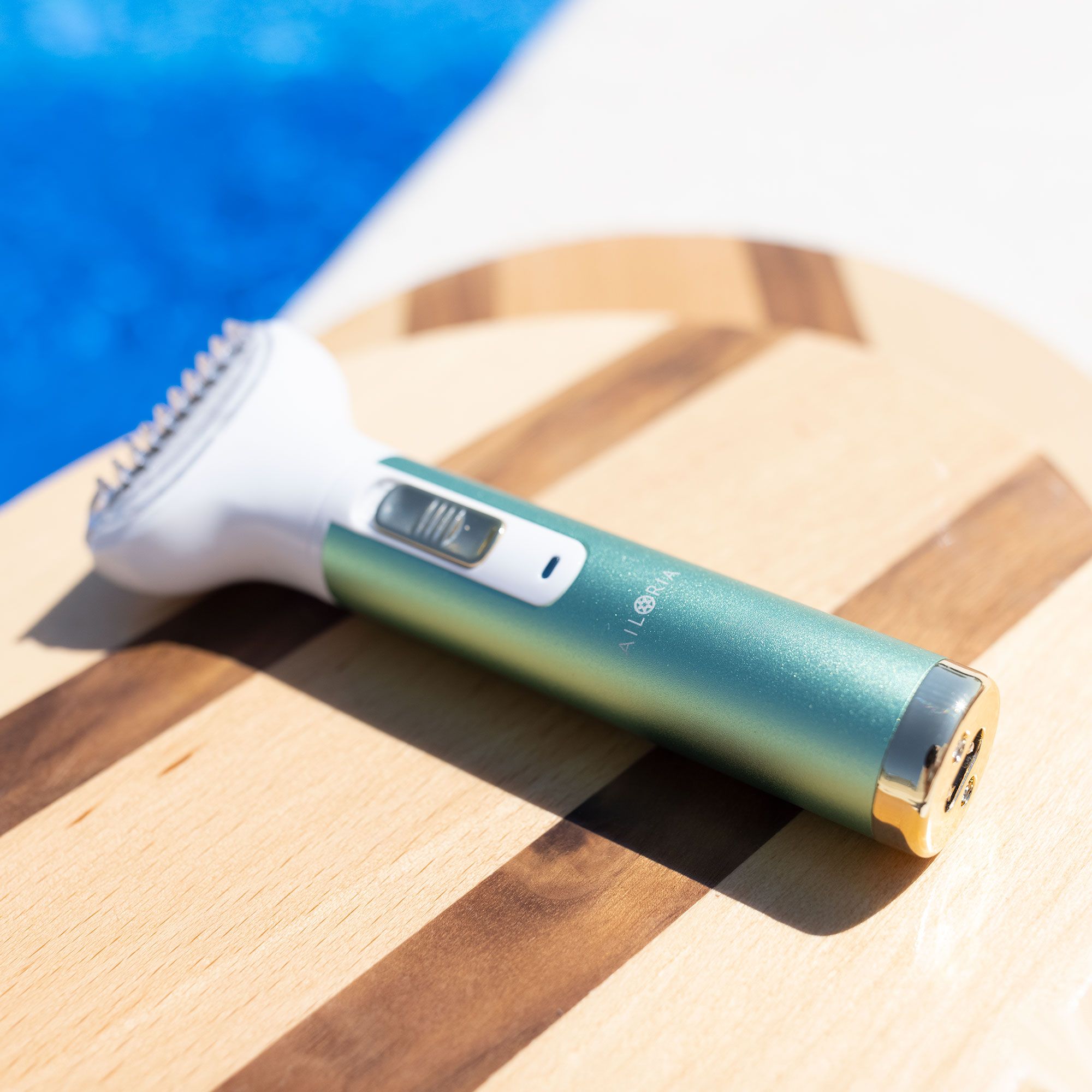 Rasoio verde e bianco su tavola di legno. Logo AILORIA visibile. Per la cura del corpo.