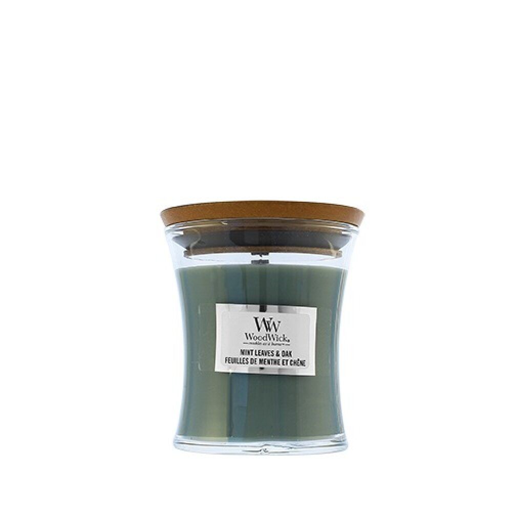 Candela verde a clessidra con coperchio in legno. Etichetta 'WoodWick', 'Mint Leaves & Oak'.