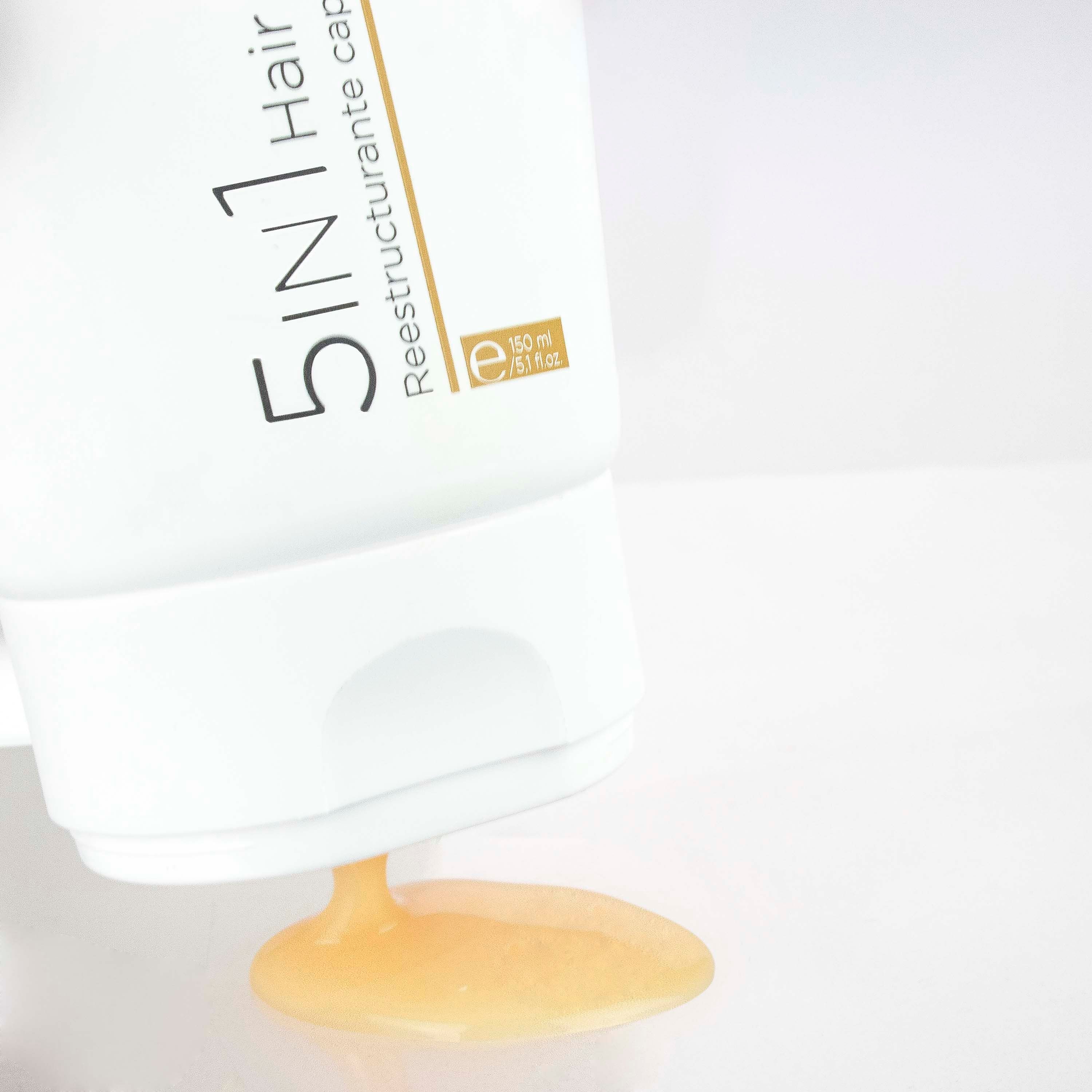 Tubo bianco, prodotto versato. Testo: 5 in 1 Hair Restorer. Marchio: Postquam. Liquido giallo.