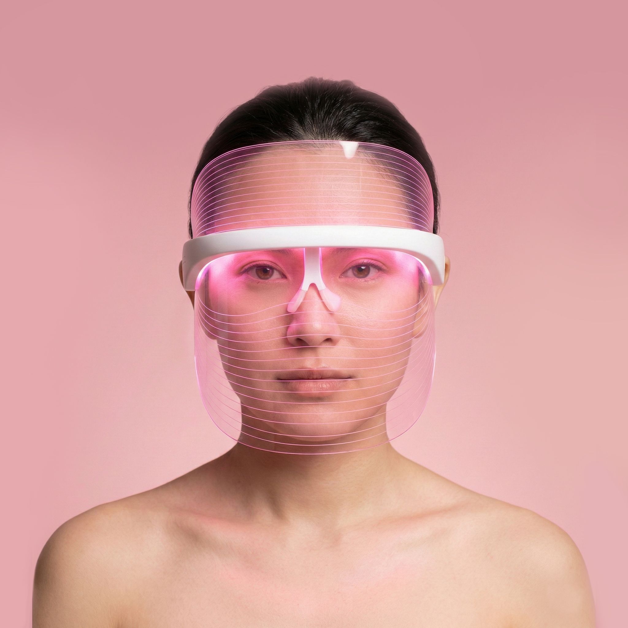 Donna con maschera facciale LED luminosa di colore rosa.