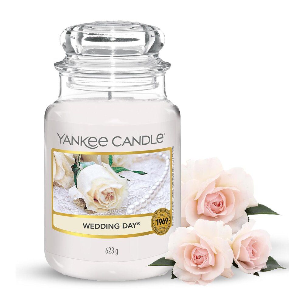 Candela in vaso con coperchio. Scritta: Yankee Candle Wedding Day. Etichetta con motivo floreale. 3 rose accanto.