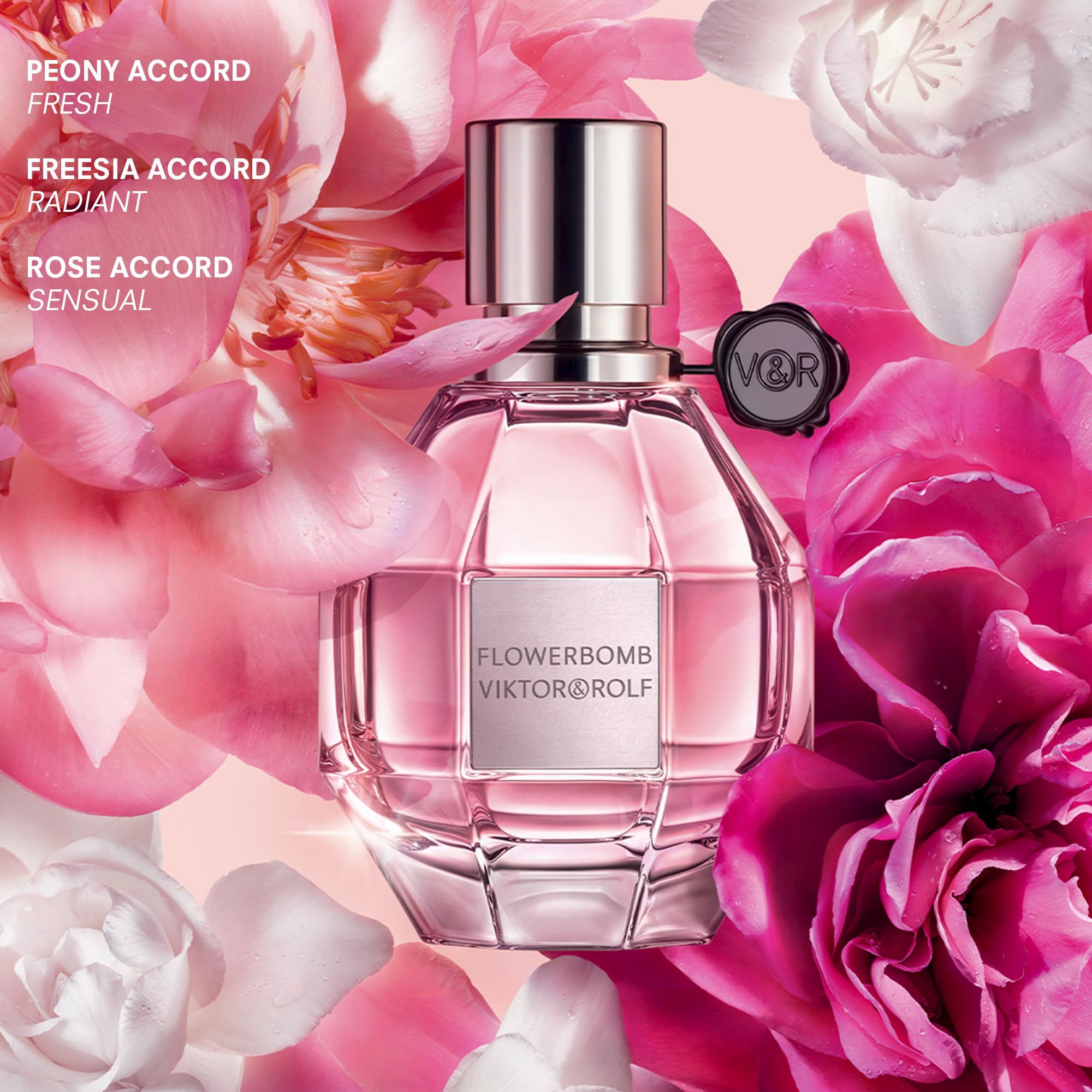 Flacone di profumo Flowerbomb di Viktor & Rolf circondato da fiori rosa e bianchi. Testo: Peony Accord, Freesia Accord, Rose Accord.