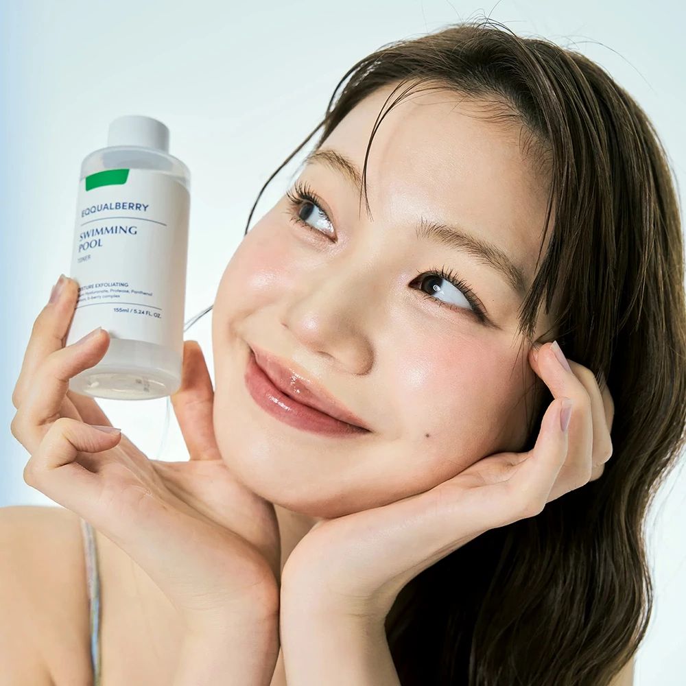 Donna tiene in mano una bottiglia di toner. Sulla bottiglia c'è scritto EQQUALBERRY Swimming Pool.