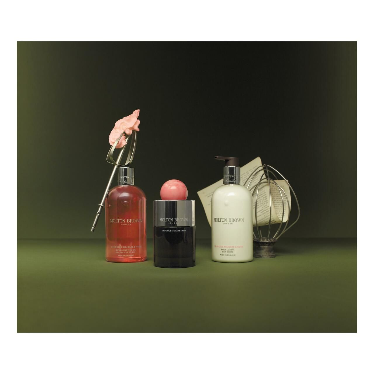 Tre bottiglie e una sfera. Scritta: Molton Brown. Sfondo verde. Elementi decorativi.
