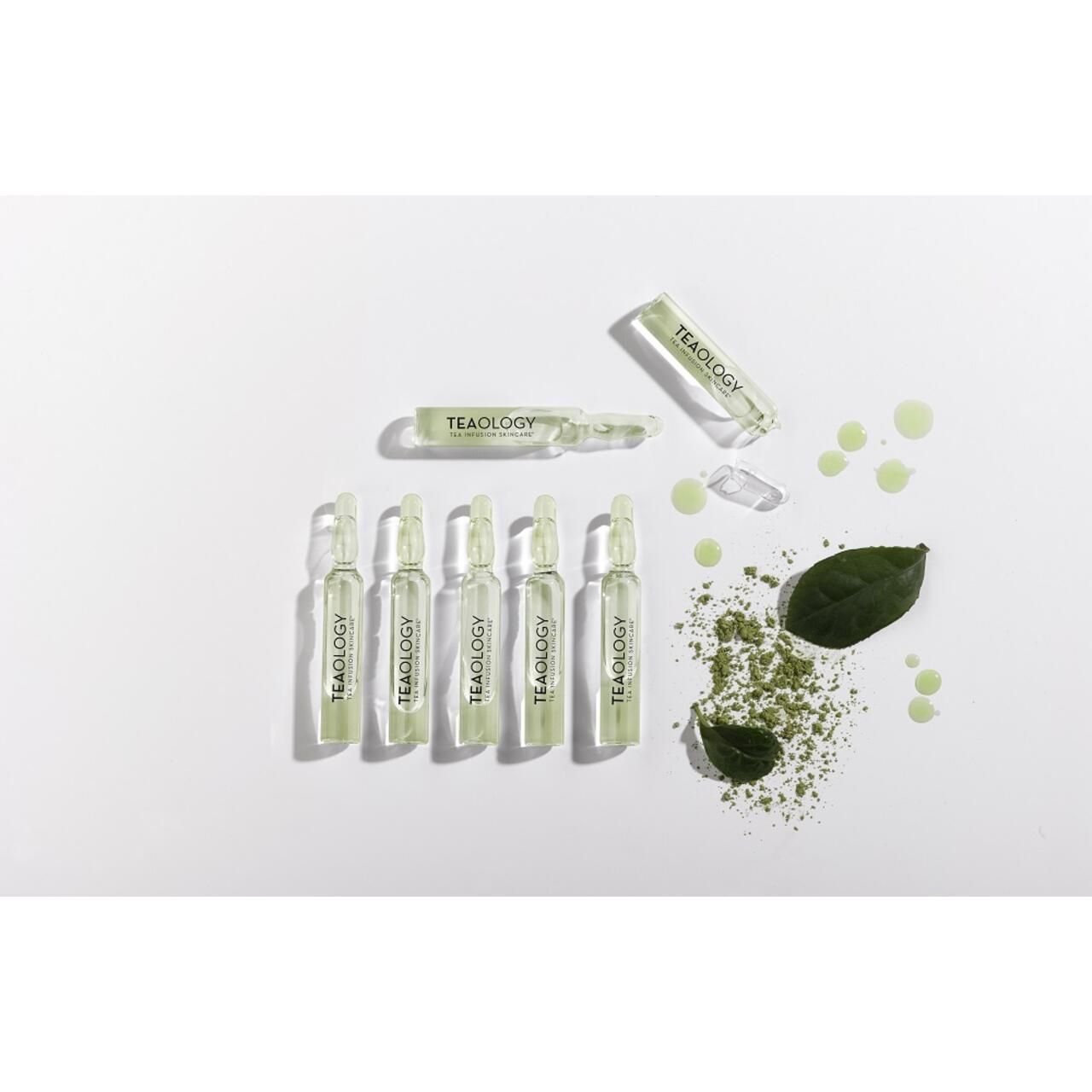 Diverse fiale Teaology Matcha Tea, polvere di matcha, foglie e gocce di liquido su sfondo bianco.