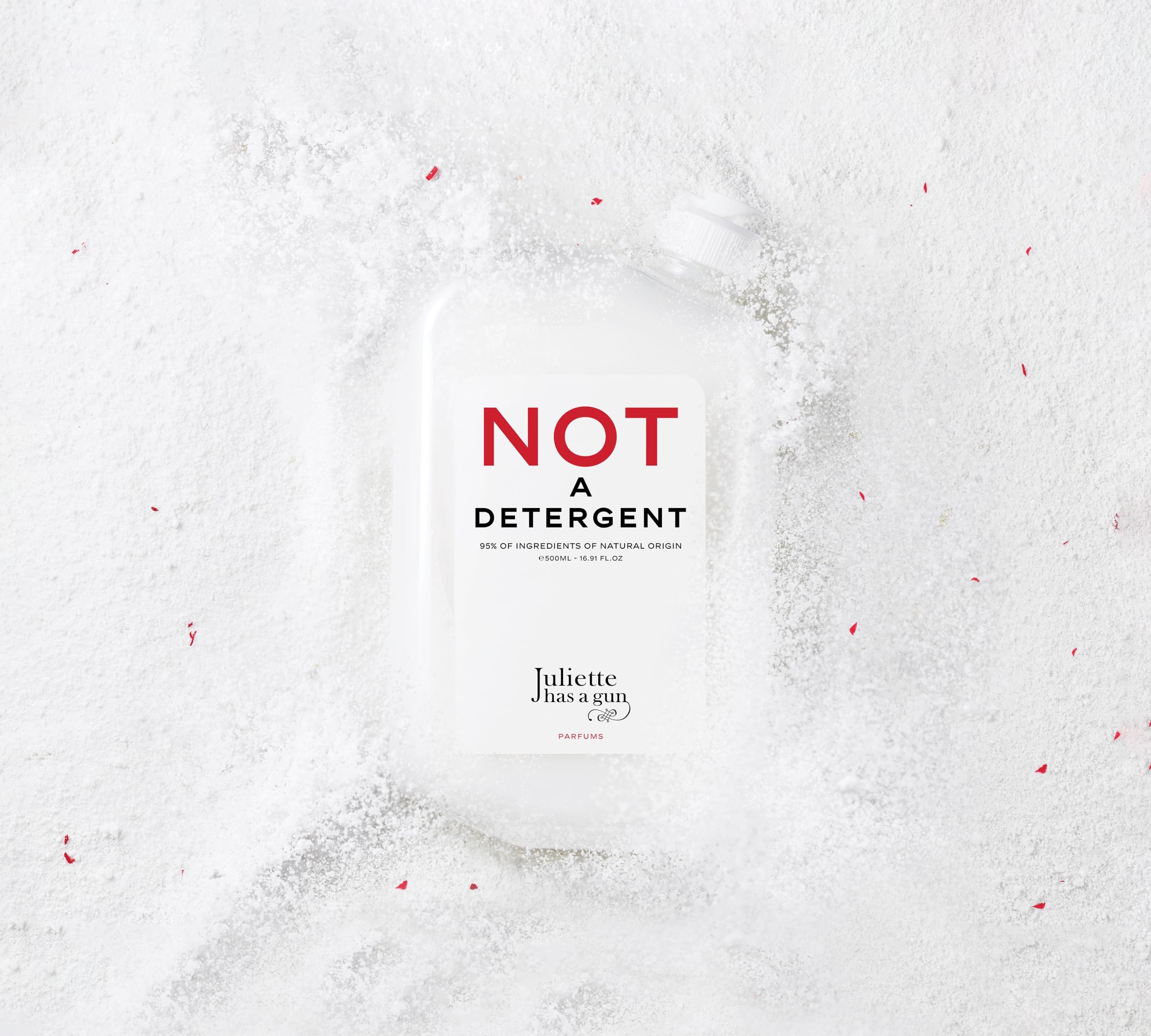 Flacone rettangolare con etichetta "NOT A DETERGENT", circondato da polvere bianca ed elementi rossi.