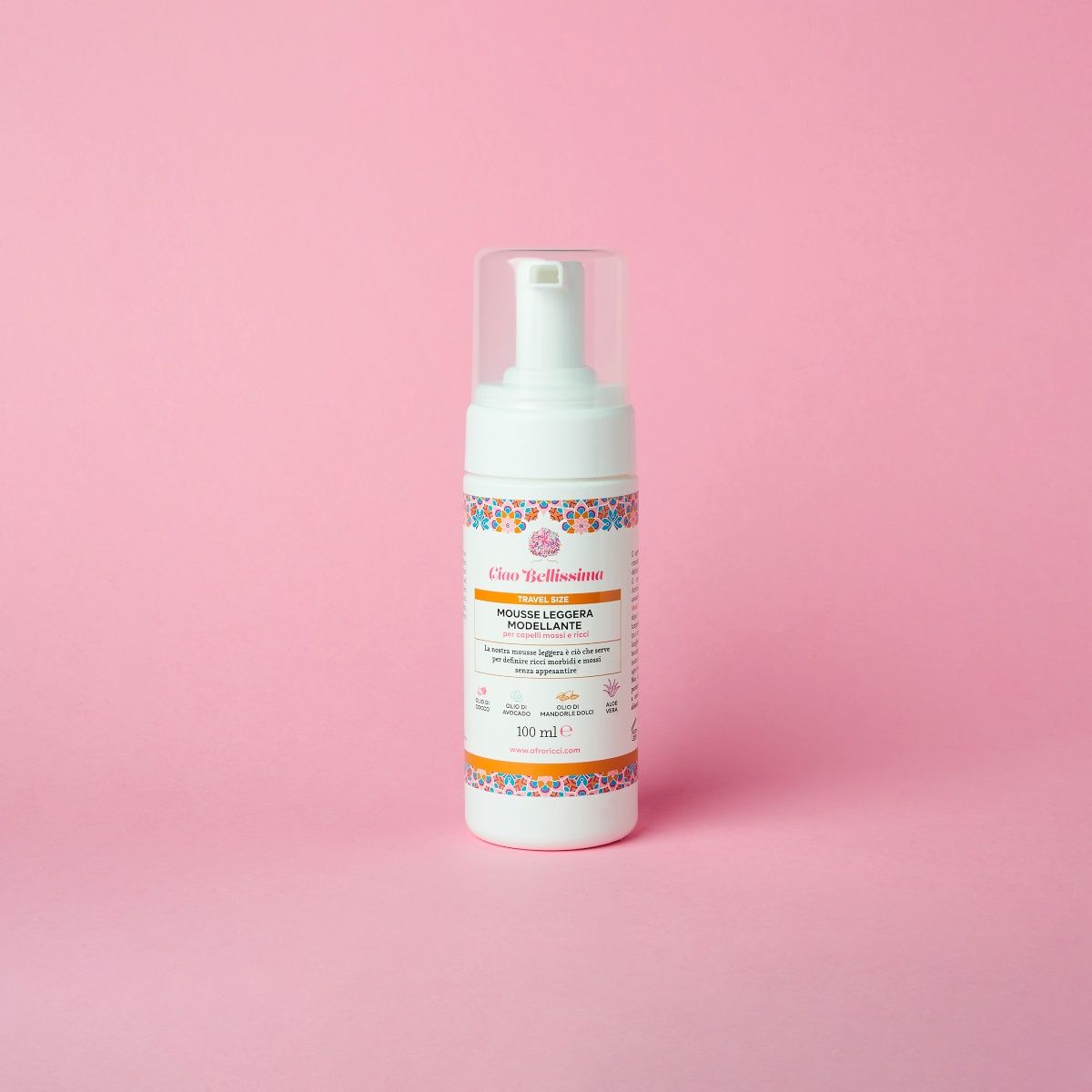 Flacone bianco con erogatore a spruzzo. Etichetta con testo e motivi floreali. Su sfondo rosa.