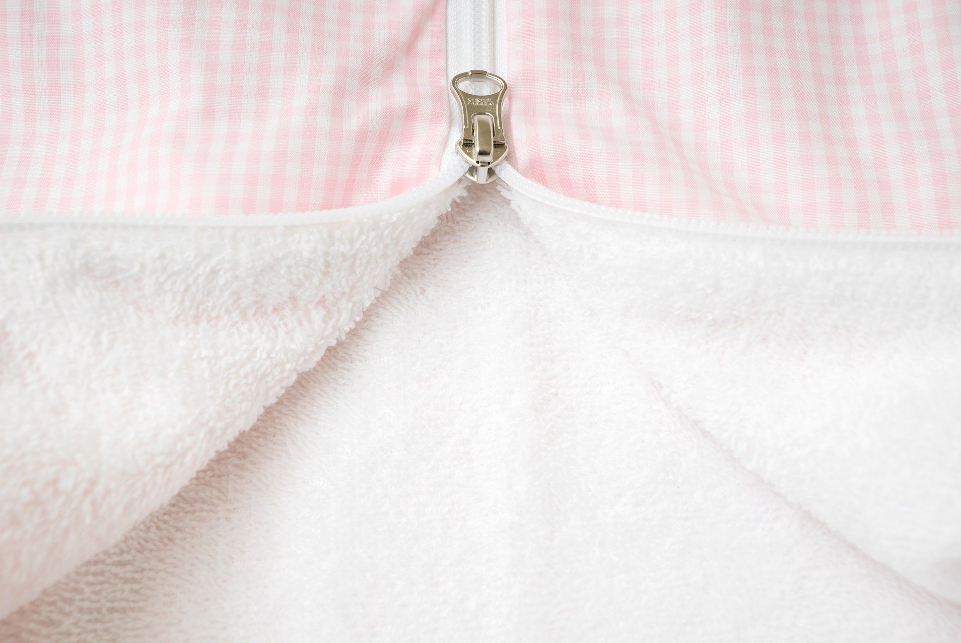 Primo piano della cerniera di un sacco nanna rosa. Interno in spugna bianca.