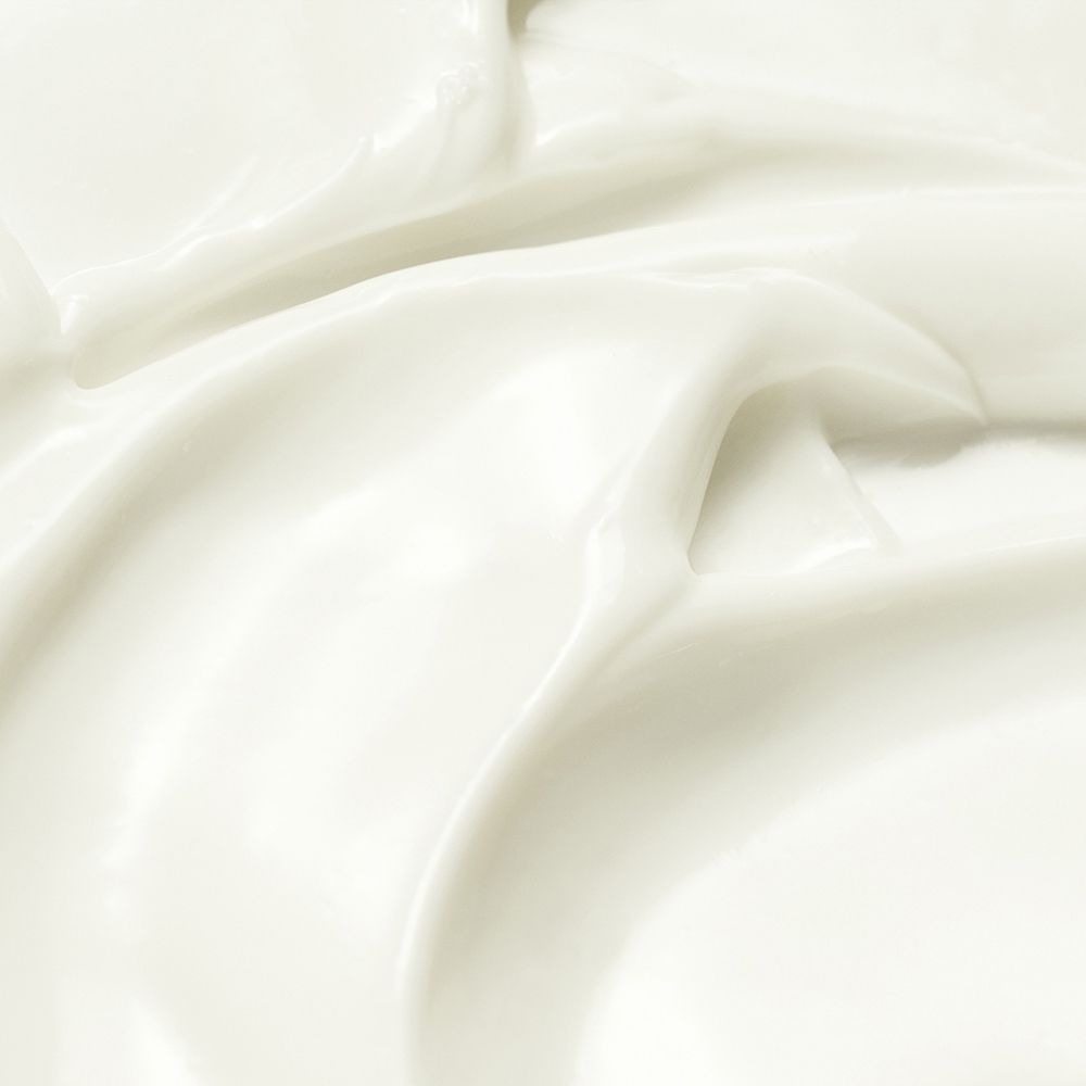 Primo piano di crema bianca. Texture liscia con dolci onde e riflessi.