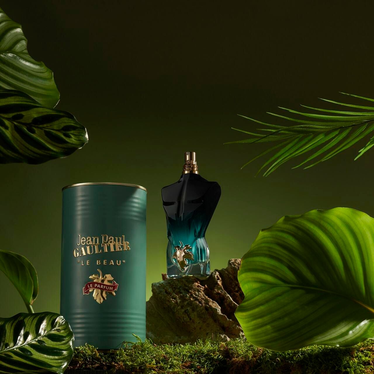 Flacone e scatola di profumo su sfondo verde con foglie. Flacone a forma di busto, scatola con logo.