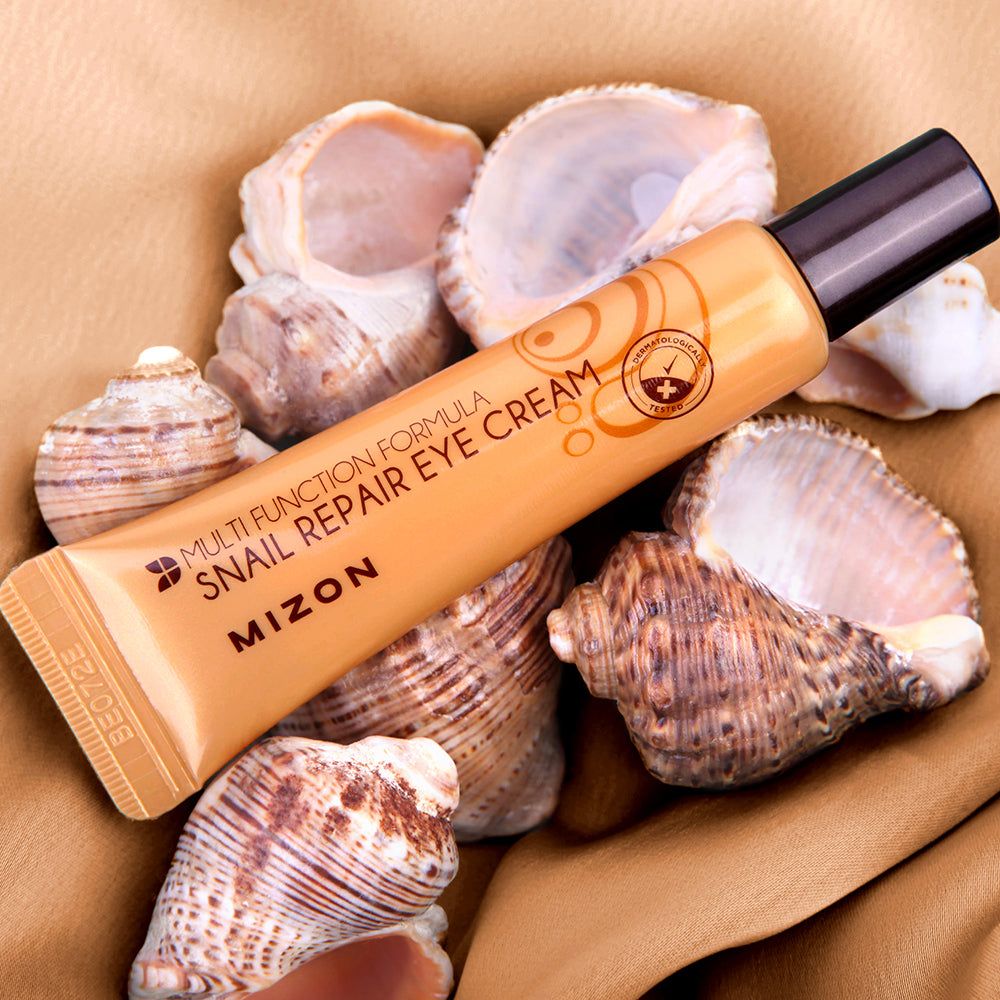 Tubo dorato con tappo nero, su conchiglie. Scritta: Mizon Snail Repair Eye Cream.