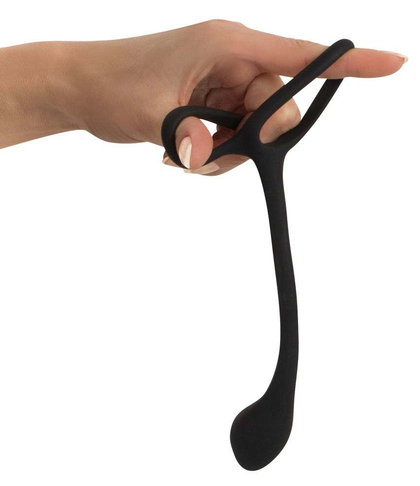 Anello per pene/testicoli nero con plug anale, tenuto da una mano. Parte ad anello e asta allungata.