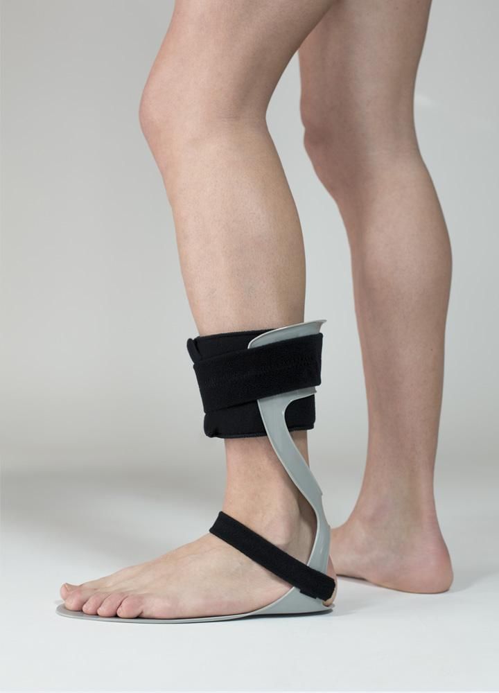 Tutore grigio per caviglia con chiusure in velcro nere, fissato alla gamba di una persona.