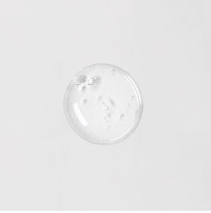 Campione di siero trasparente e rotondo su sfondo bianco. Piccole bolle visibili.
