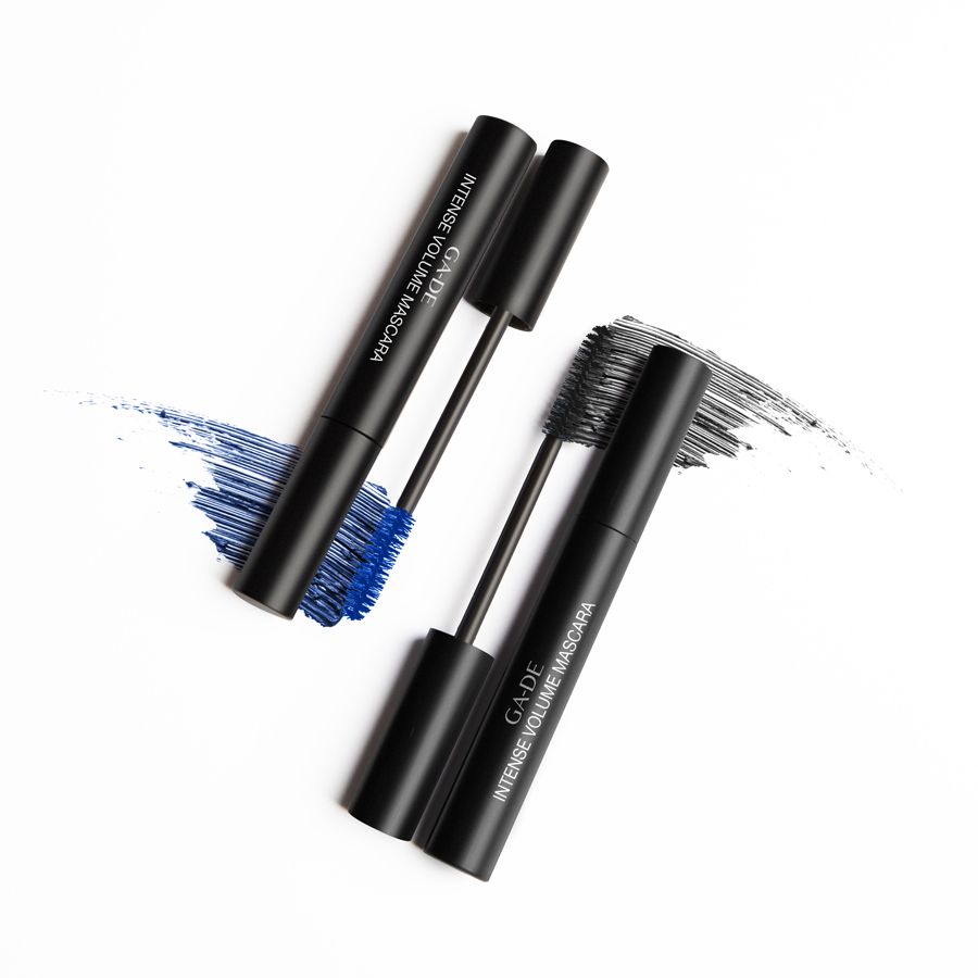 Due tubi di mascara neri con spazzole. Scritta: GA-DE Intense Volume Mascara. Tracce blu e nere.