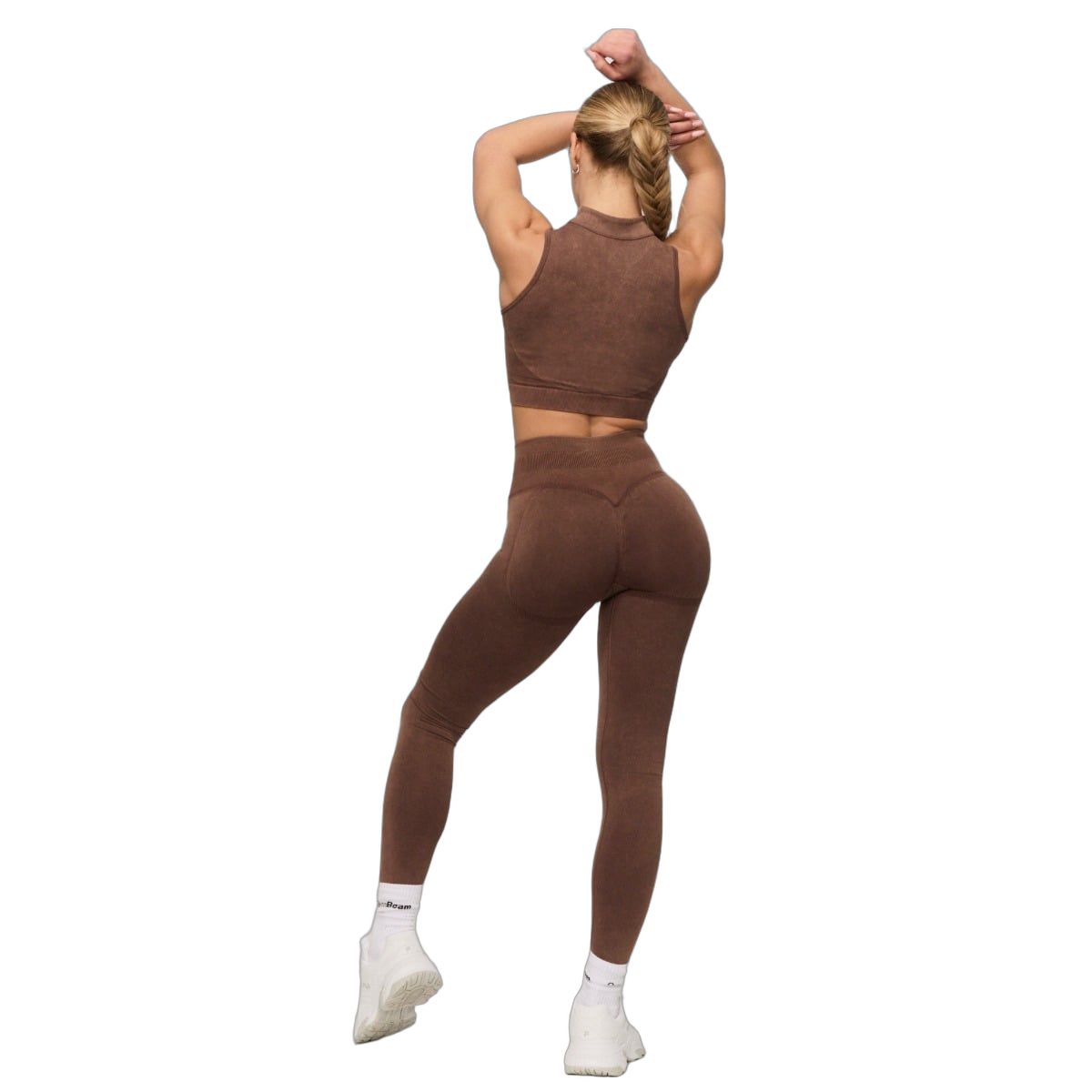 Vista posteriore di una donna con leggings marroni senza cuciture a vita alta e reggiseno sportivo abbinato.