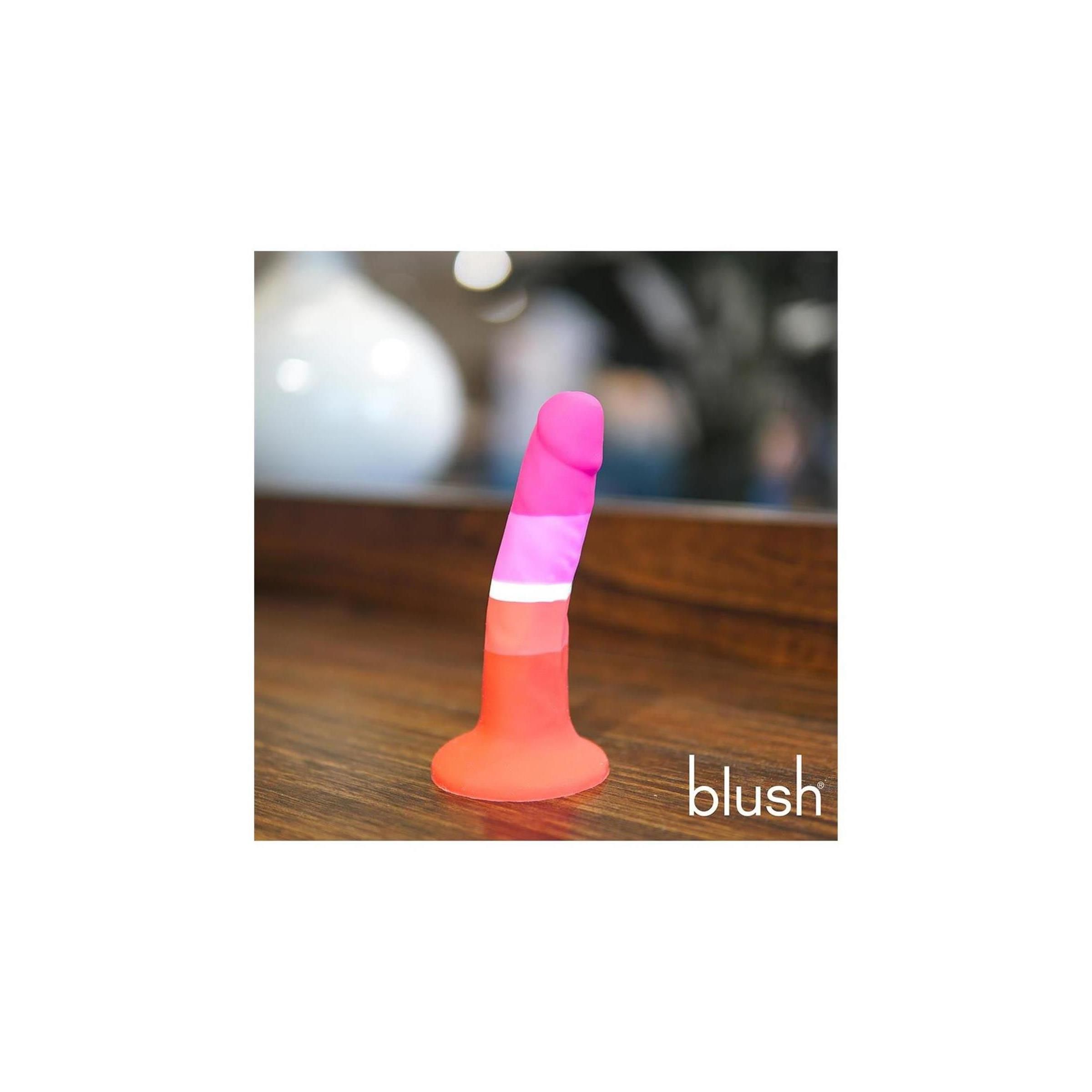 Dildo multicolore. Colori: rosa, bianco, arancione e rosso. Base e punta arrotondate. Marchio "blush" visibile.