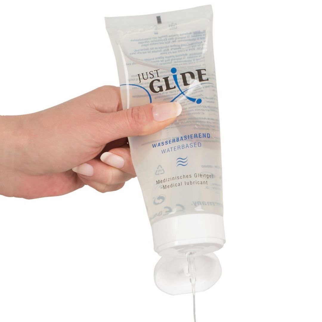 Mano che tiene un tubetto, da cui fuoriesce gel. Scritta: JUST GLIDE, a base d'acqua, gel lubrificante medico.