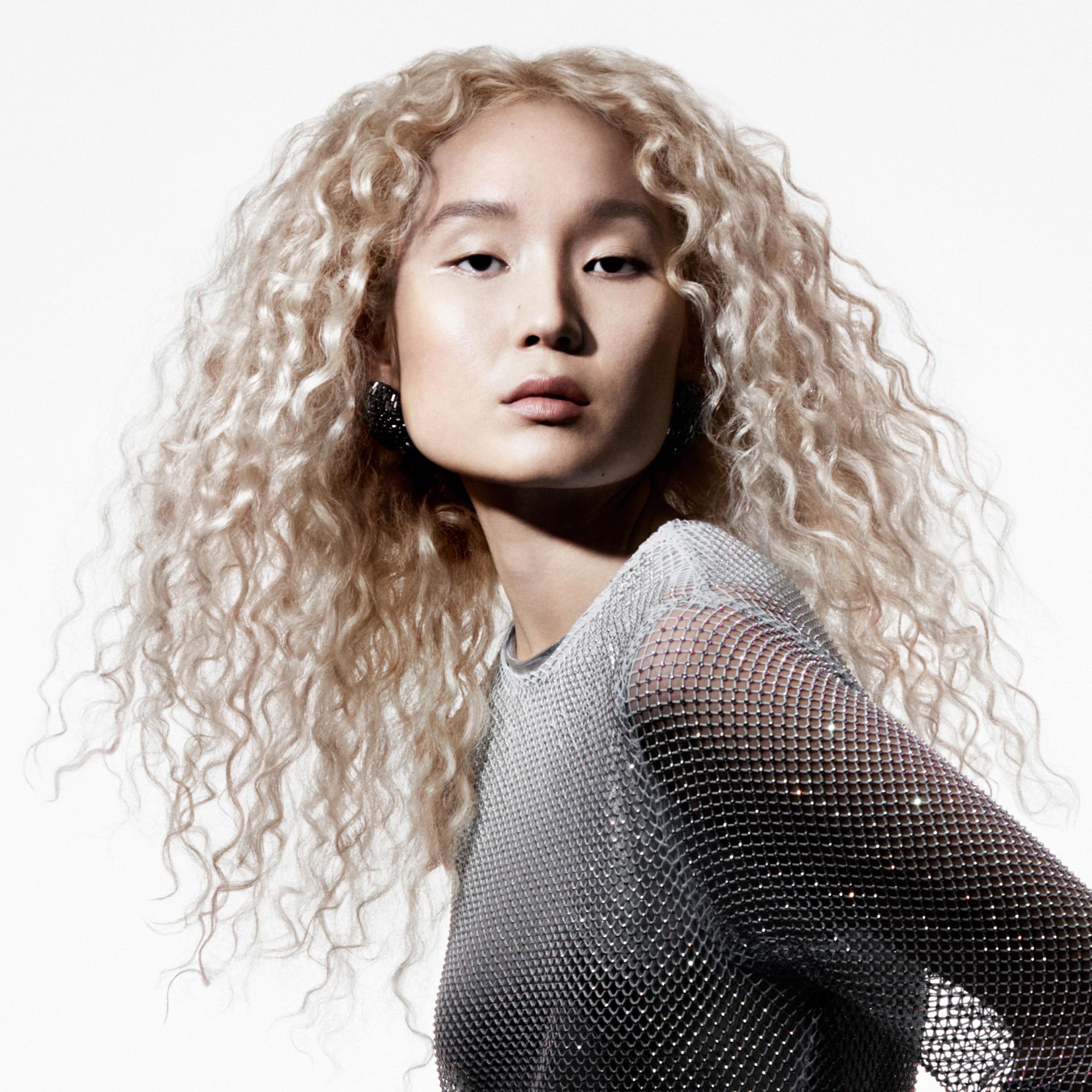 Ritratto di donna con ricci biondi. Indossa un top argentato.