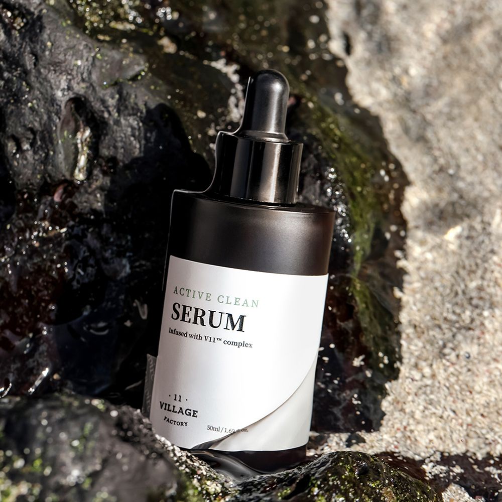 Flacone di siero marrone con tappo nero e contagocce. Etichetta con nome del prodotto e logo. Posizionato su rocce.